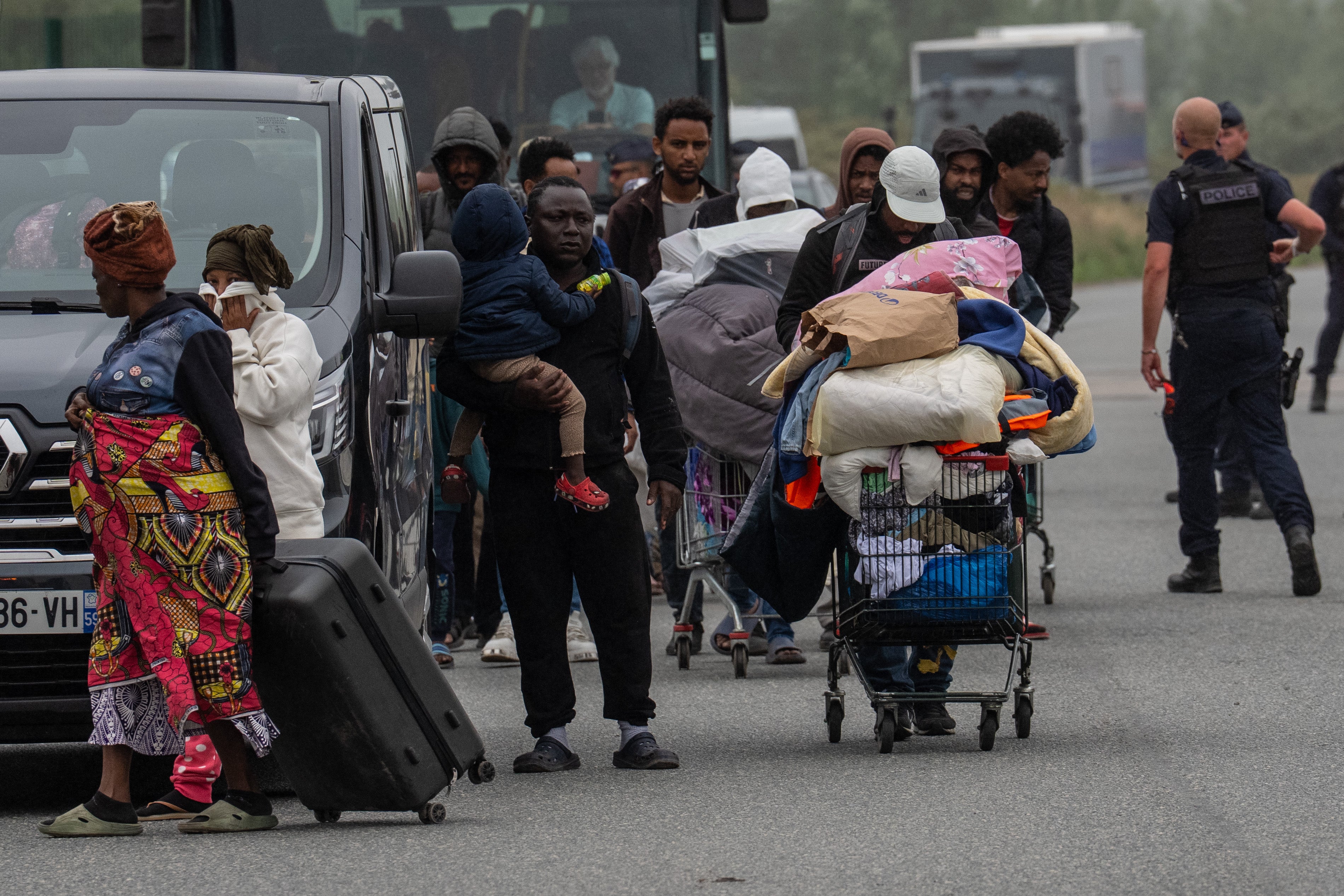 Migrants leave an area of their camp that was cleared by French authorities on July 2, 2026 in Loon-Plage, France.