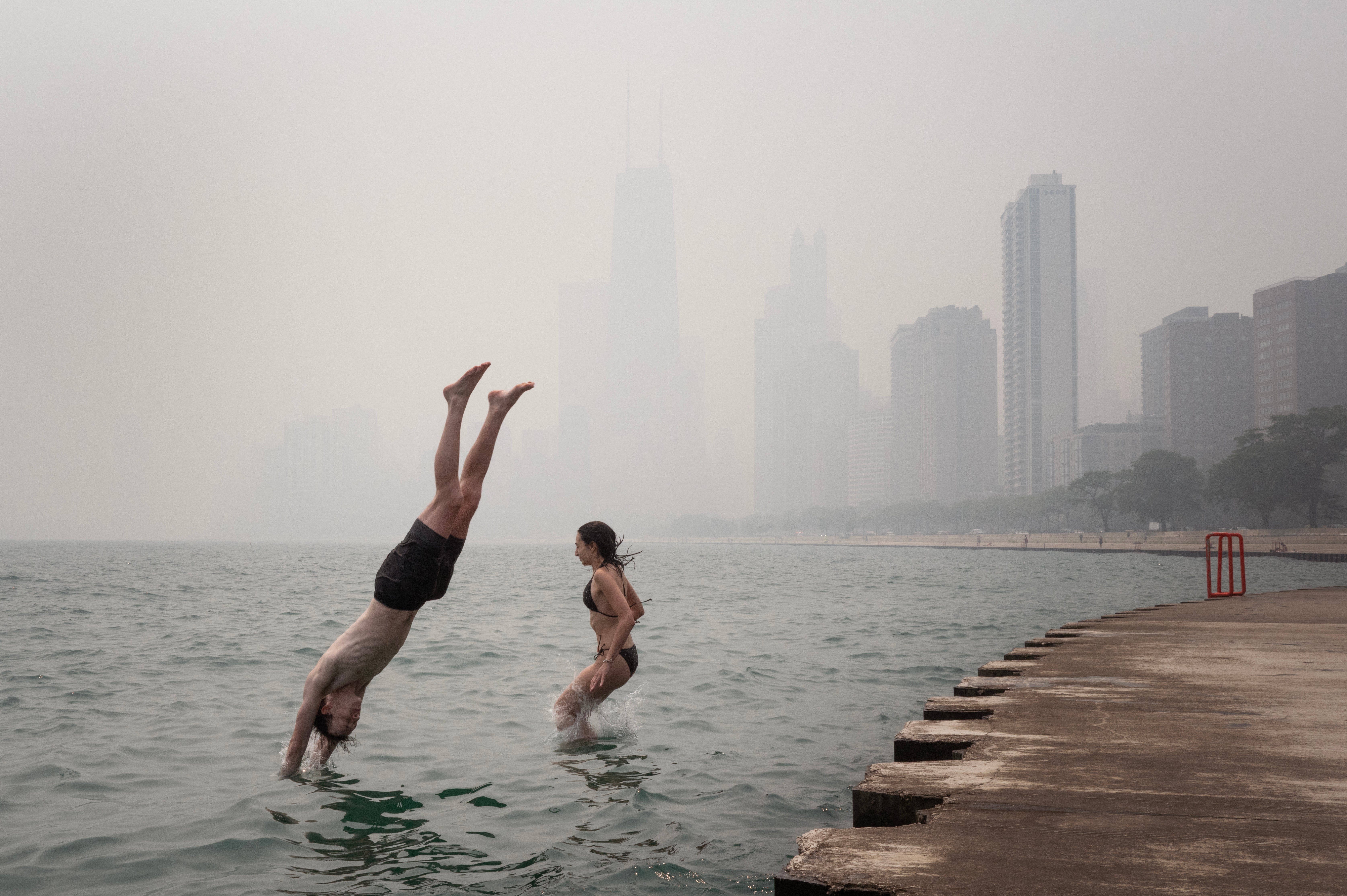 Smoke from Canadian wildfires settles in on the lakefront as Emma Kristin and Joshua Nieman cool off in Lake Michigan on July 16, 2026 in Chicago, Illinois.