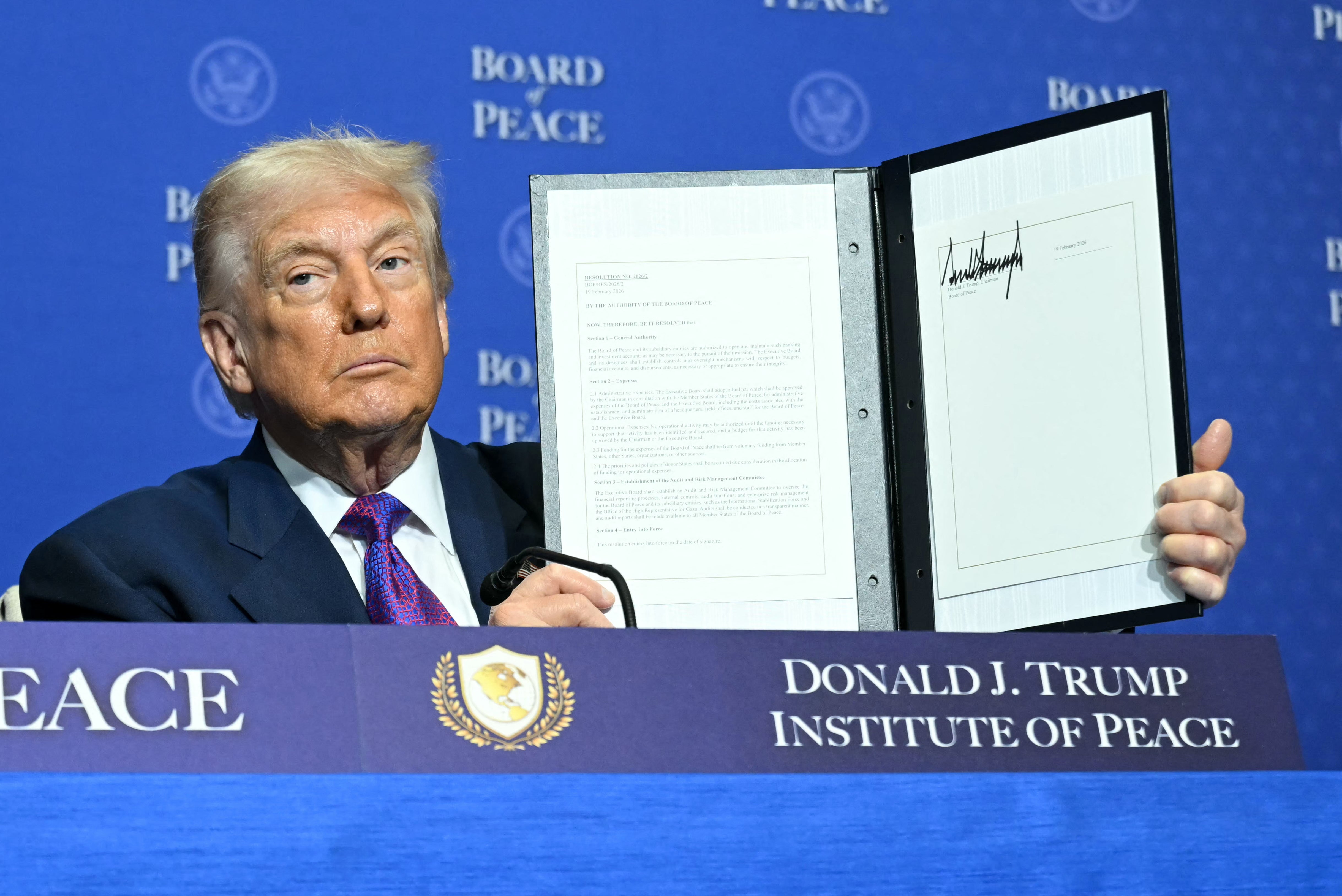 US President Donald Trump holds up a resolution document that he signed during the inaugural meeting of the "Board of Peace" at the US Institute of Peace in Washington, DC, on February 19, 2026