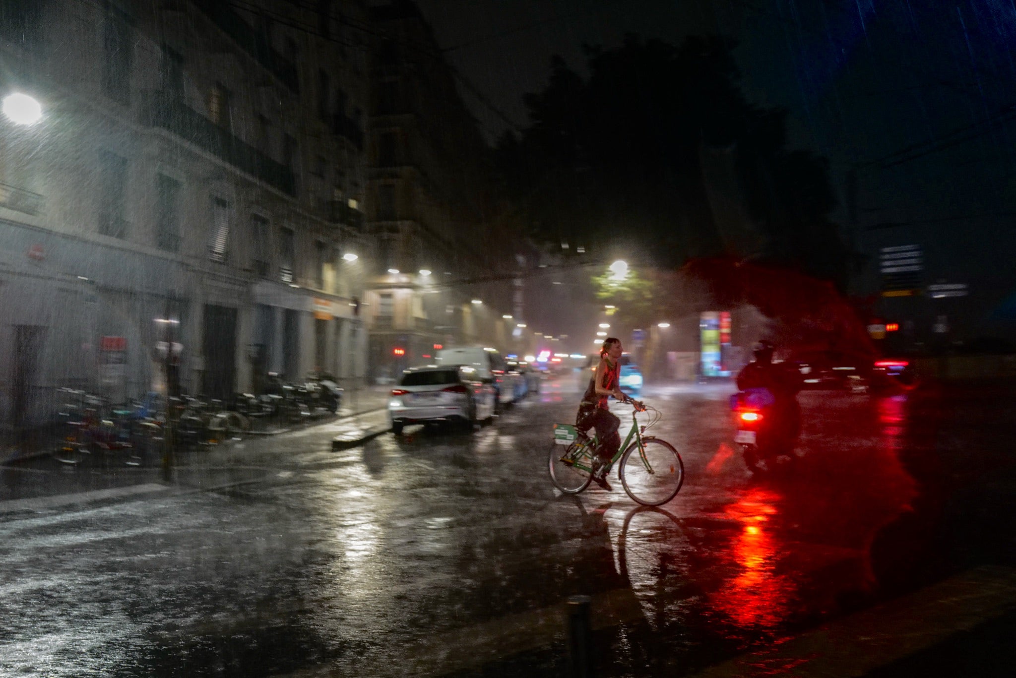 A woman rides a bicycle during a rainstorm in central Lyon on 16 July, 2026