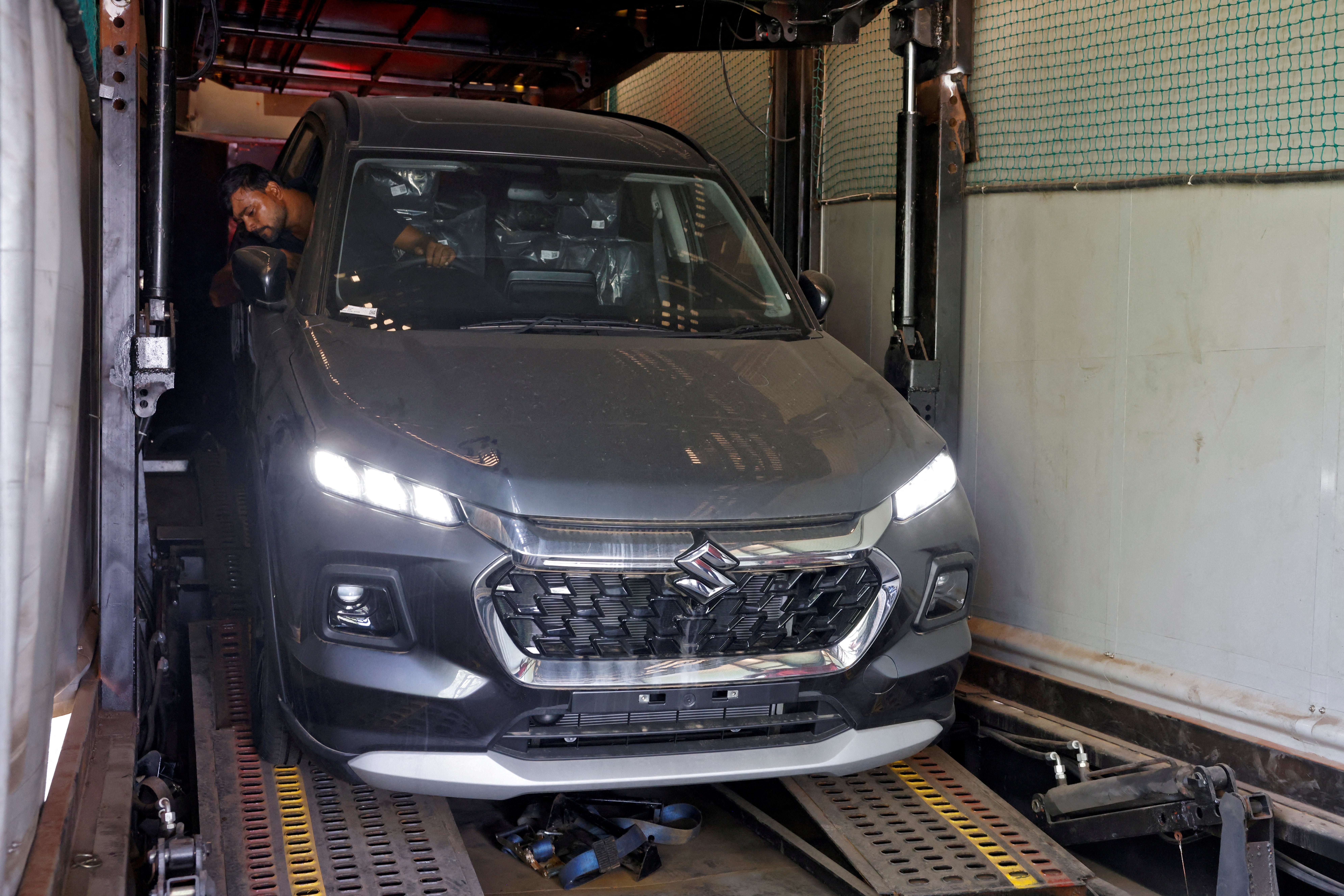 A worker unloads a Grand Vitara car from a container at a Maruti Suzuki stockyard on the outskirts of Ahmedabad, India
