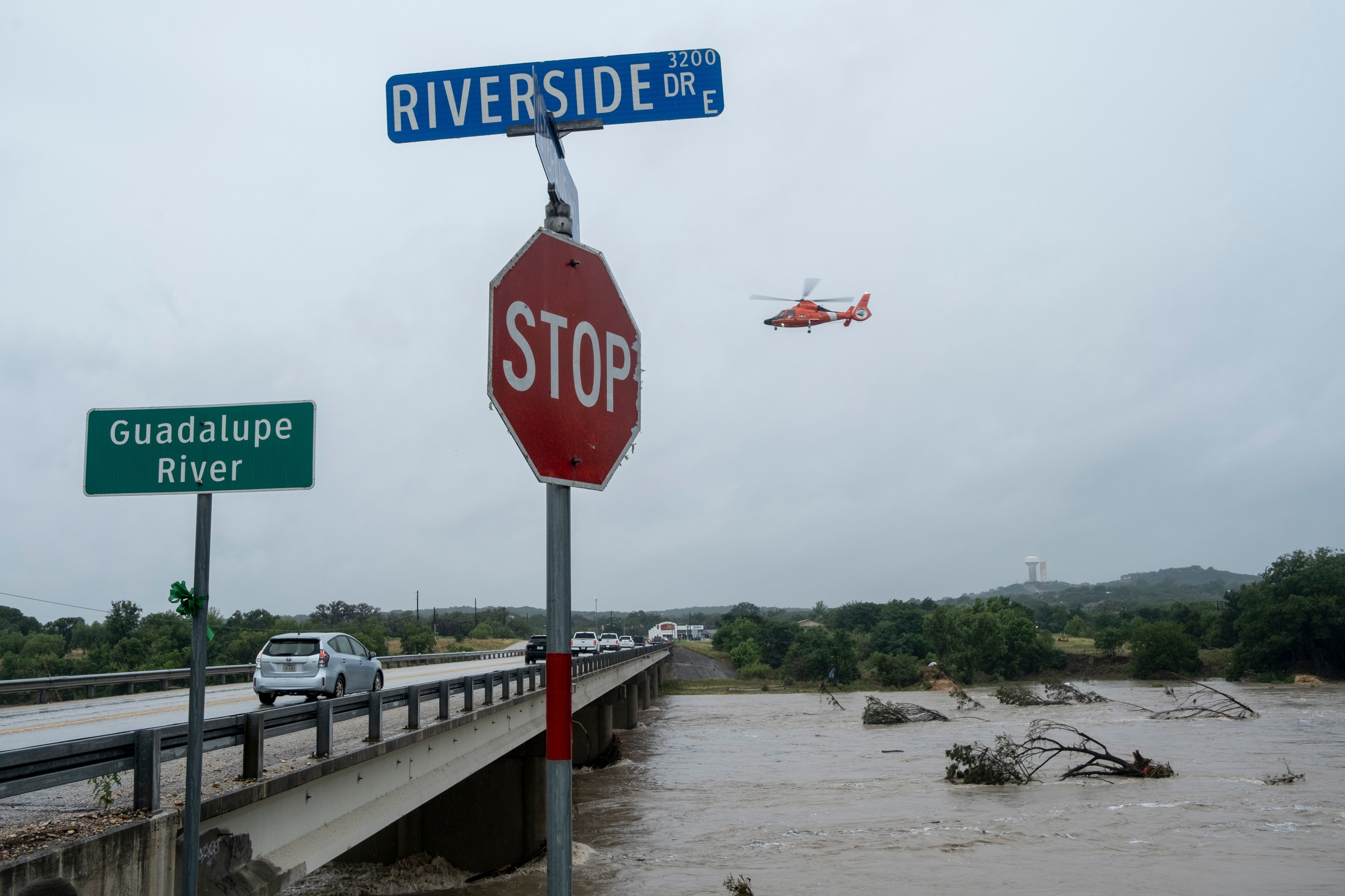 A helicopter flies over the Guadalupe River as floods pass through the area on Thursday
