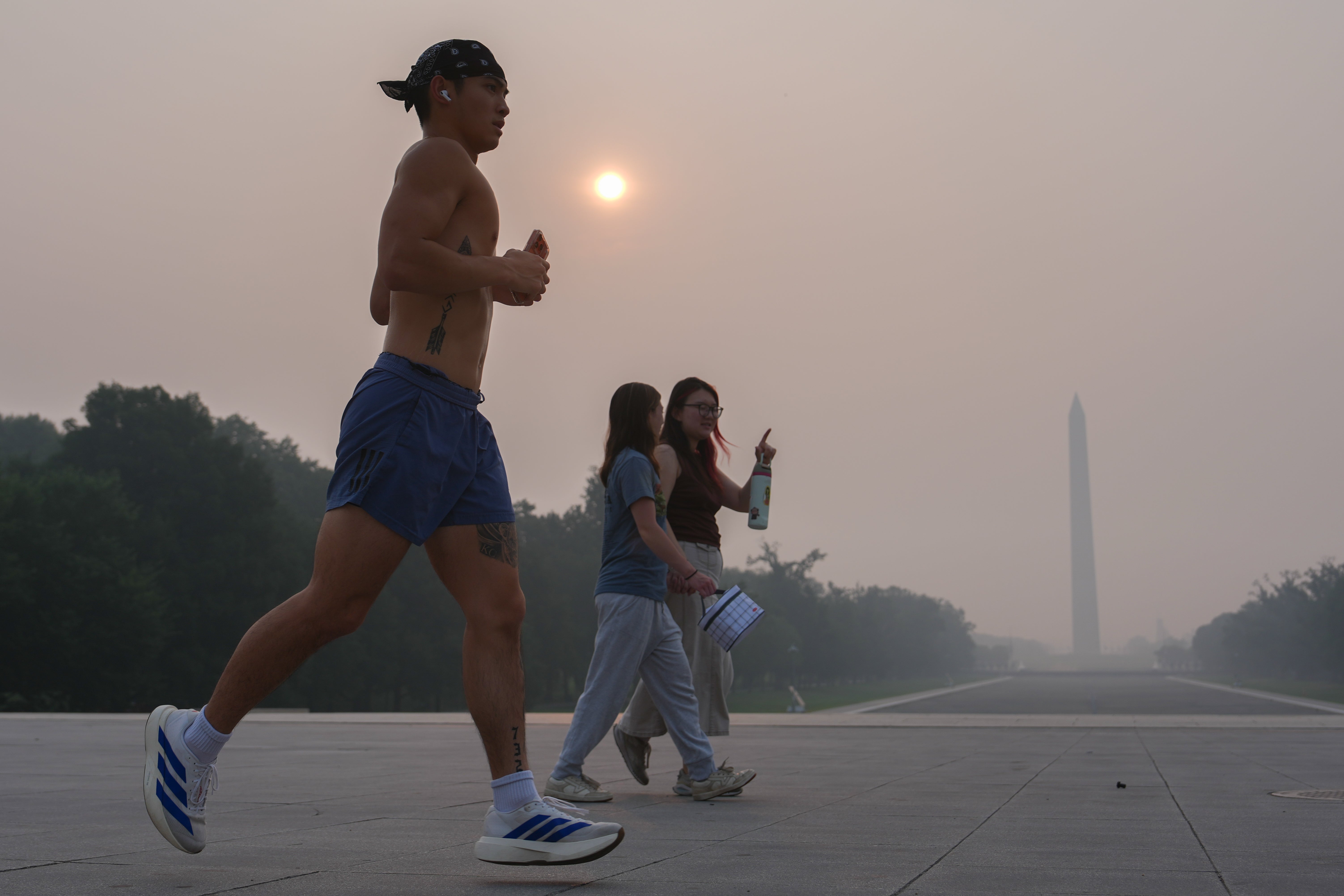 The sun is obscured by wildfire smoke as people work out near the Washington Monument and Lincoln Memorial Reflecting Pool in Washington, D.C., Friday. Wildfire smoke is harmful for many facets of our health