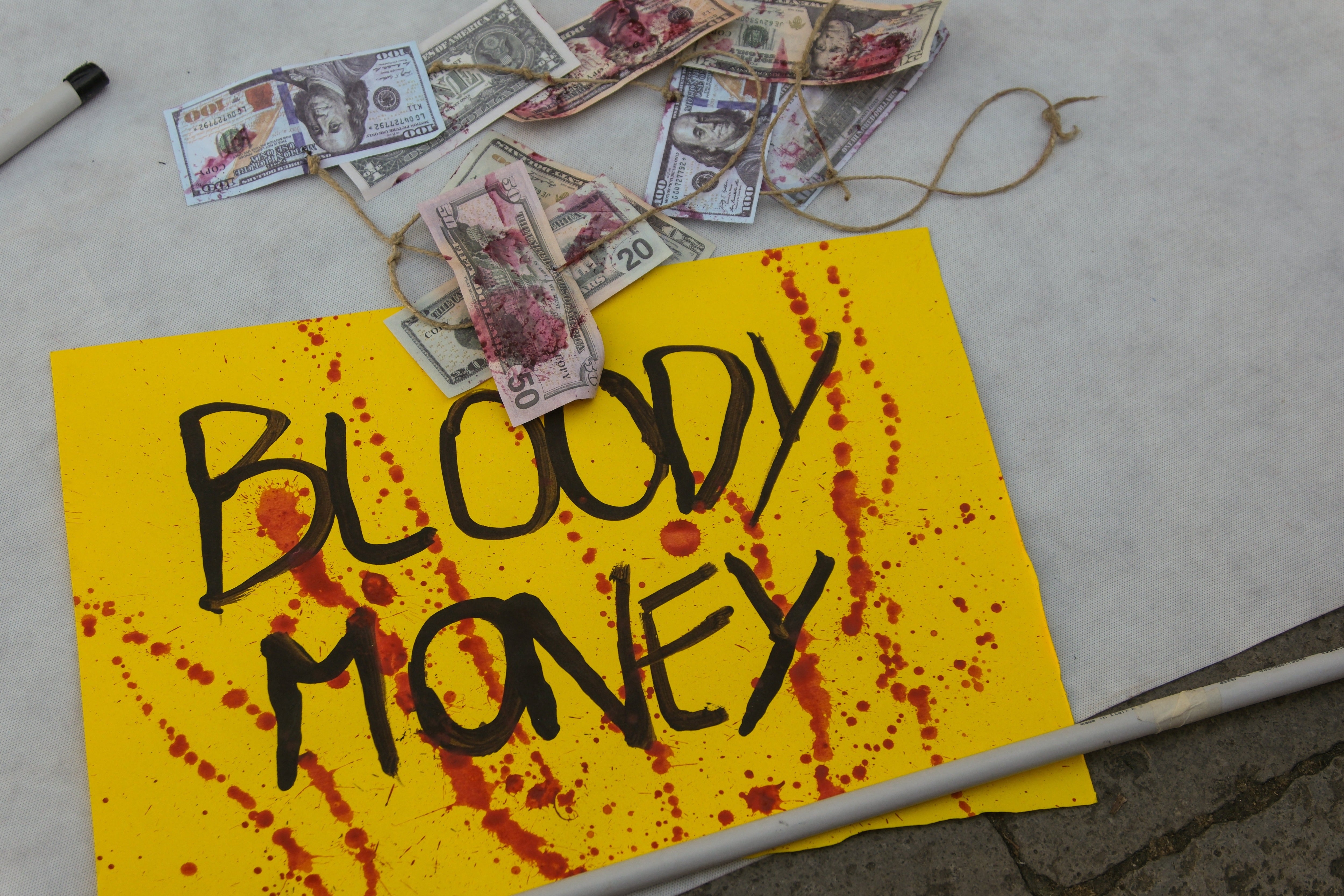 A placard and banknotes stained with red paint to represent blood lie on the ground during the protest against Fertitta’s visit