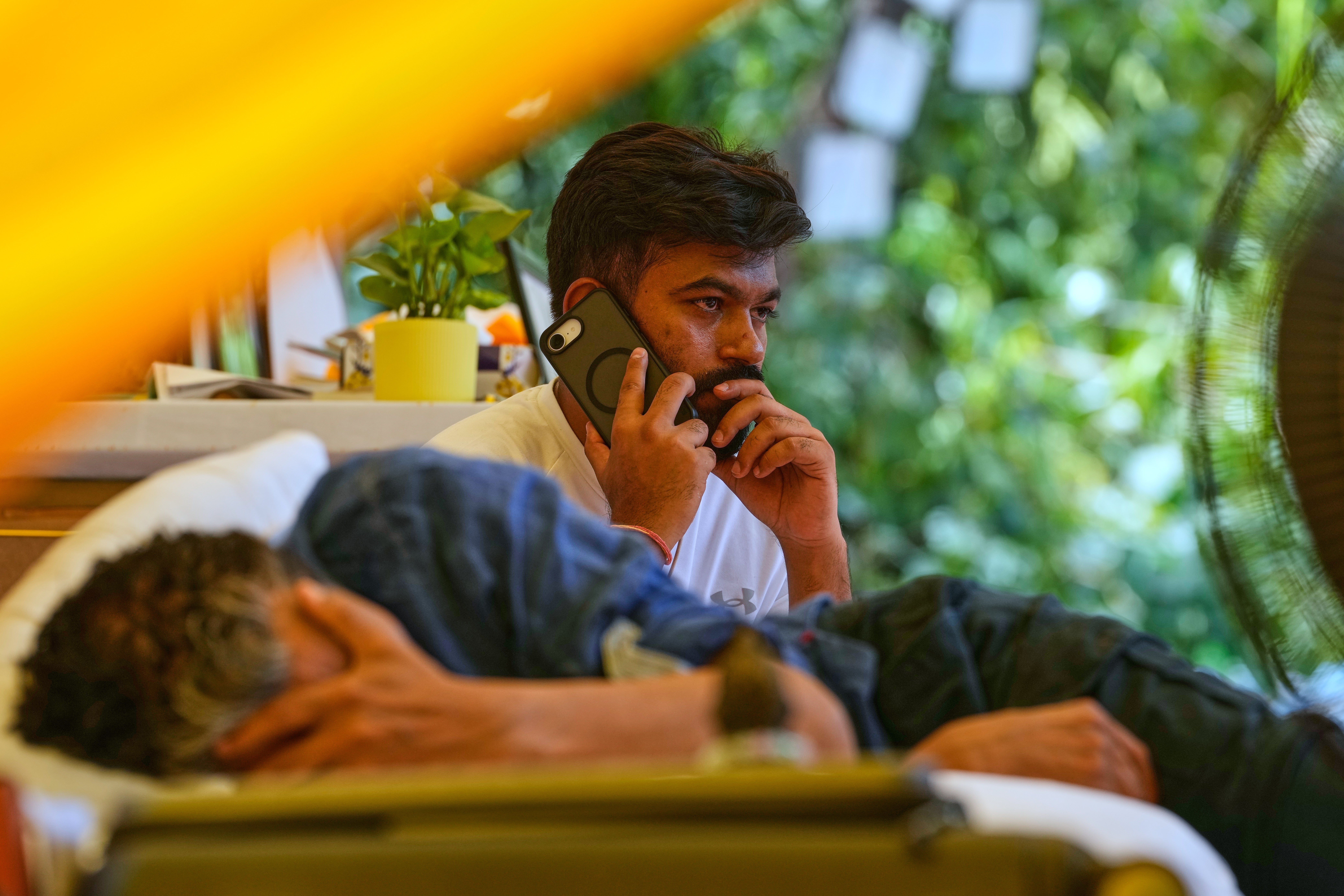 Abhijeet Dipke, founder of the Cockroach Janta Party, talks on his mobile phone as educationist and climate activist Sonam Wangchuk lies beside him