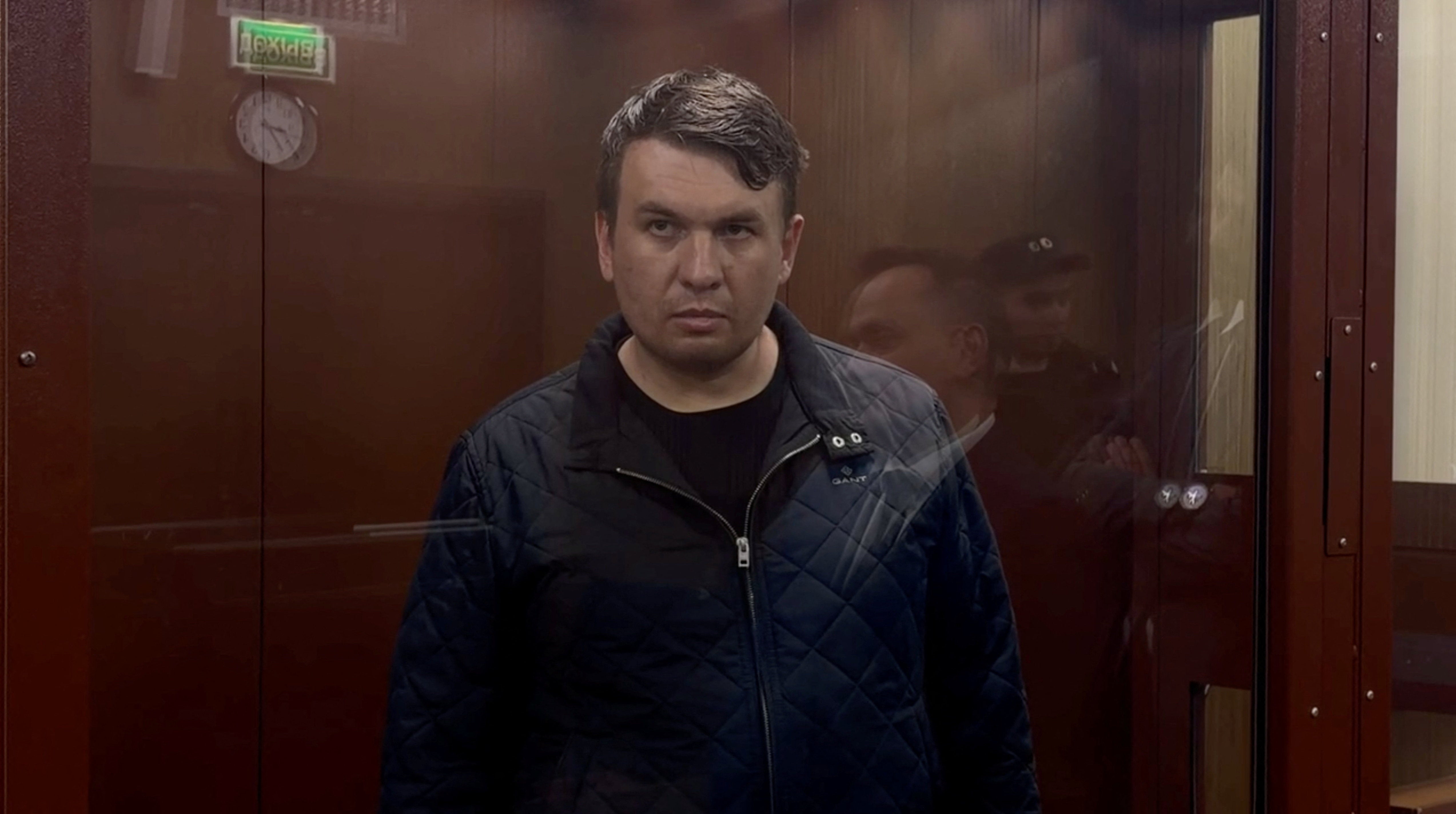 Russian blogger Ilya Remeslo, who has been accused of spreading false information about the armed forces, looks on inside a defendants' cage during a court hearing on his detention in Moscow