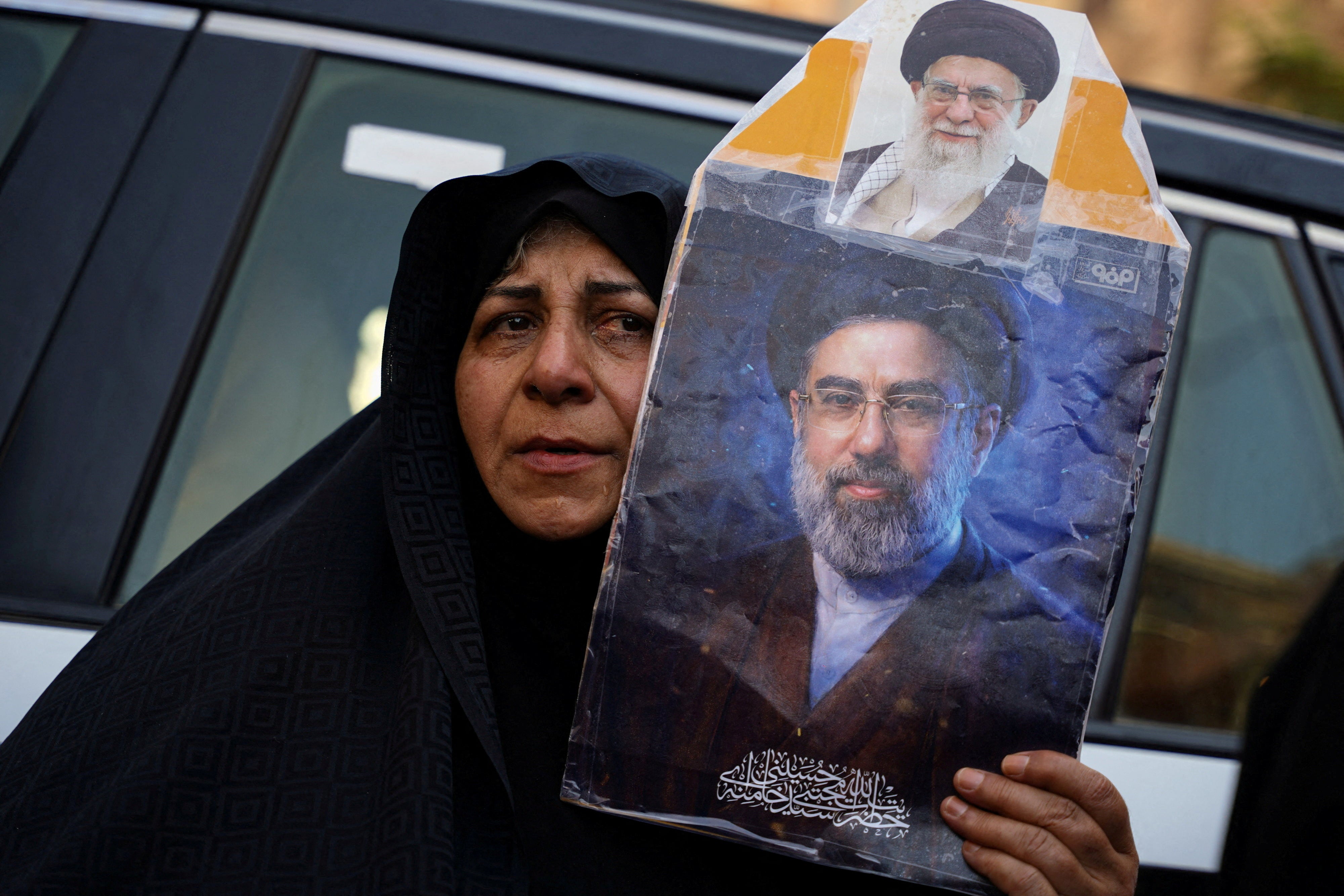 A woman holds a portrait of Iran’s Supreme Leader Mojtaba Khamenei and Iran’s late Supreme Leader Ayatollah Ali Khamenei