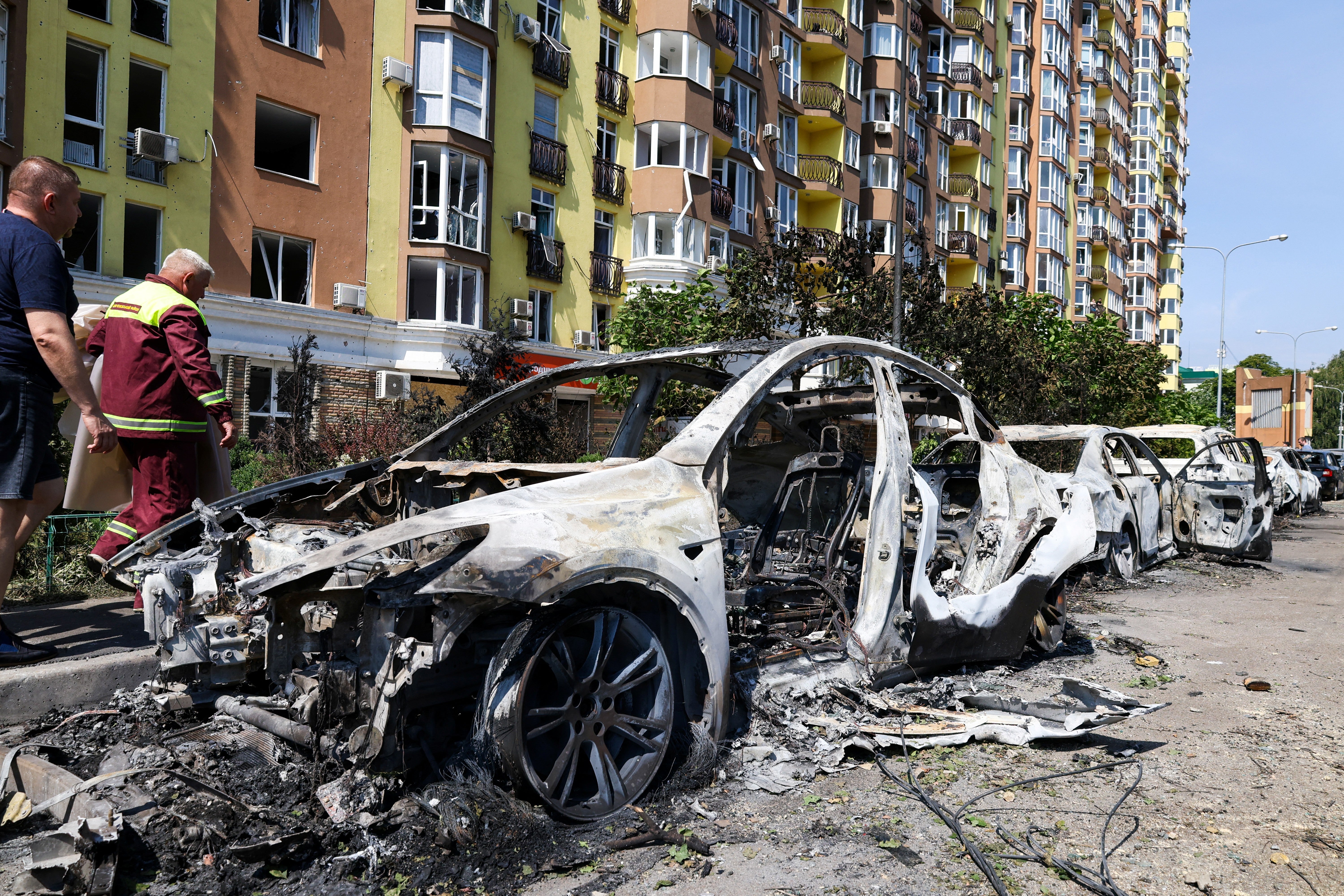 La gente pasa junto a coches dañados estacionados en una calle tras los ataques con misiles en Kiev