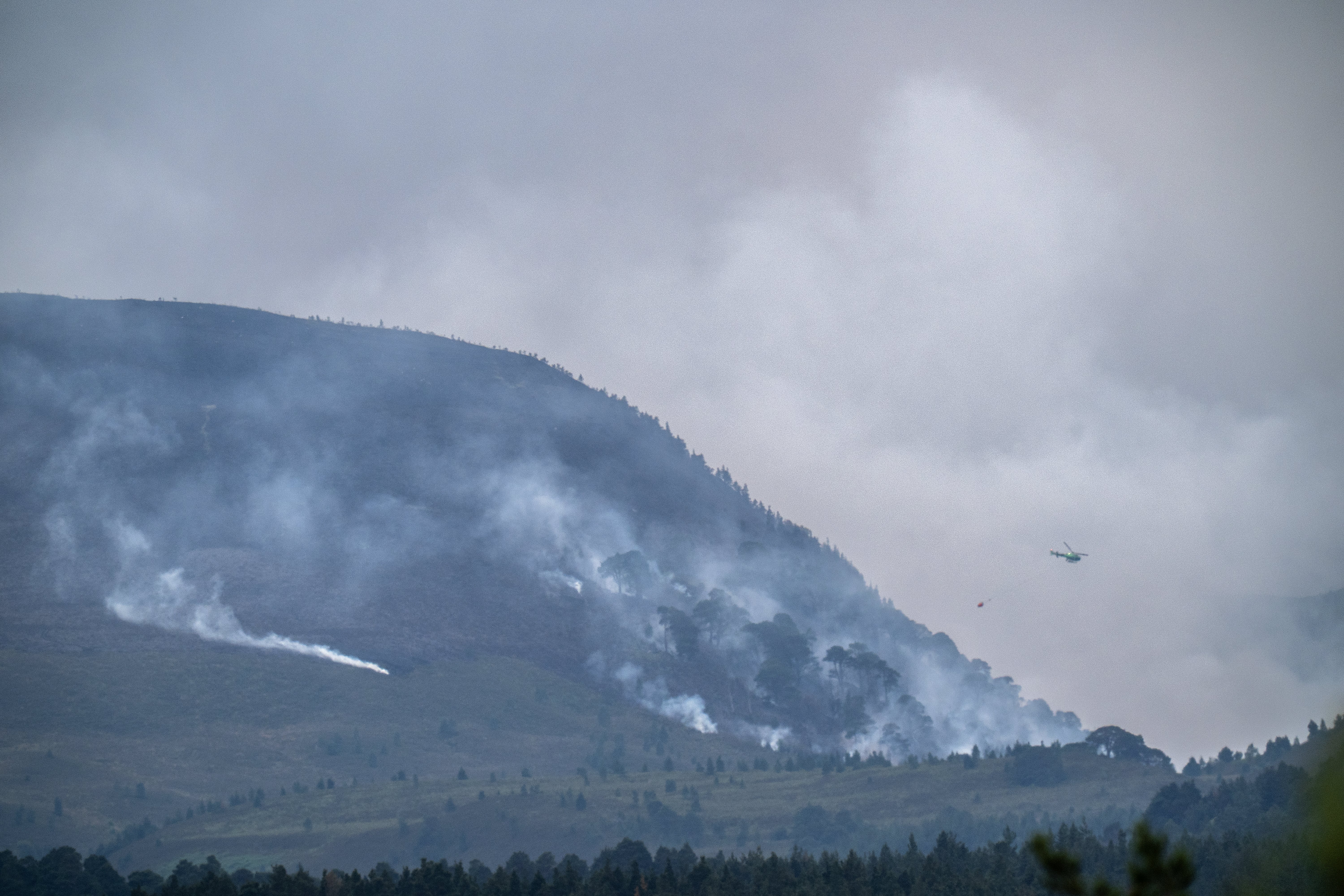 A helicopter carrying water tackles the wildfire burning near Nethy Bridge in the Cairngorms National Park in northeast Scotland (Jane Barlow/PA) (PA Wire)