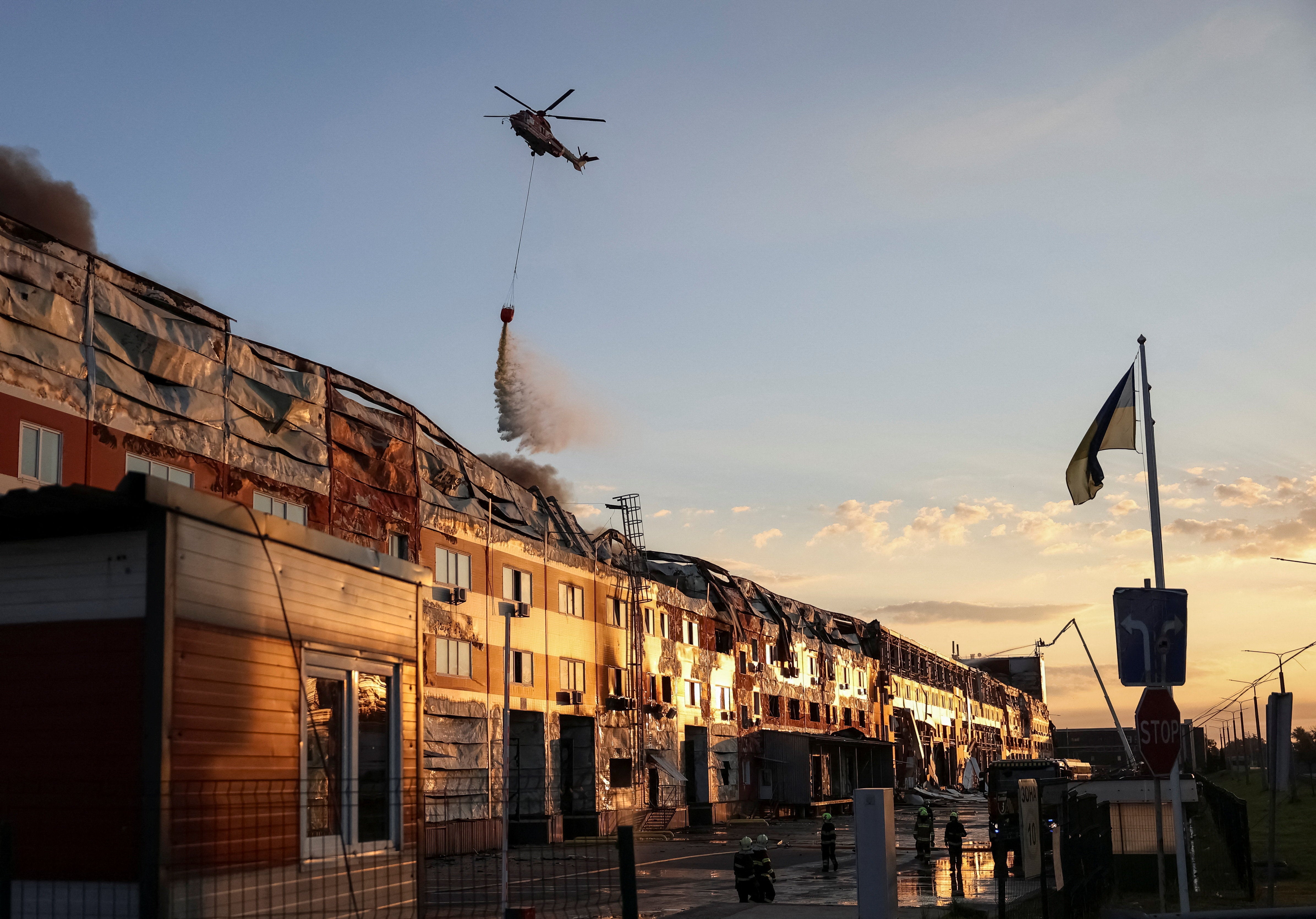 A firefighting helicopter drops water over the site of a Russian missile strike in Kyiv