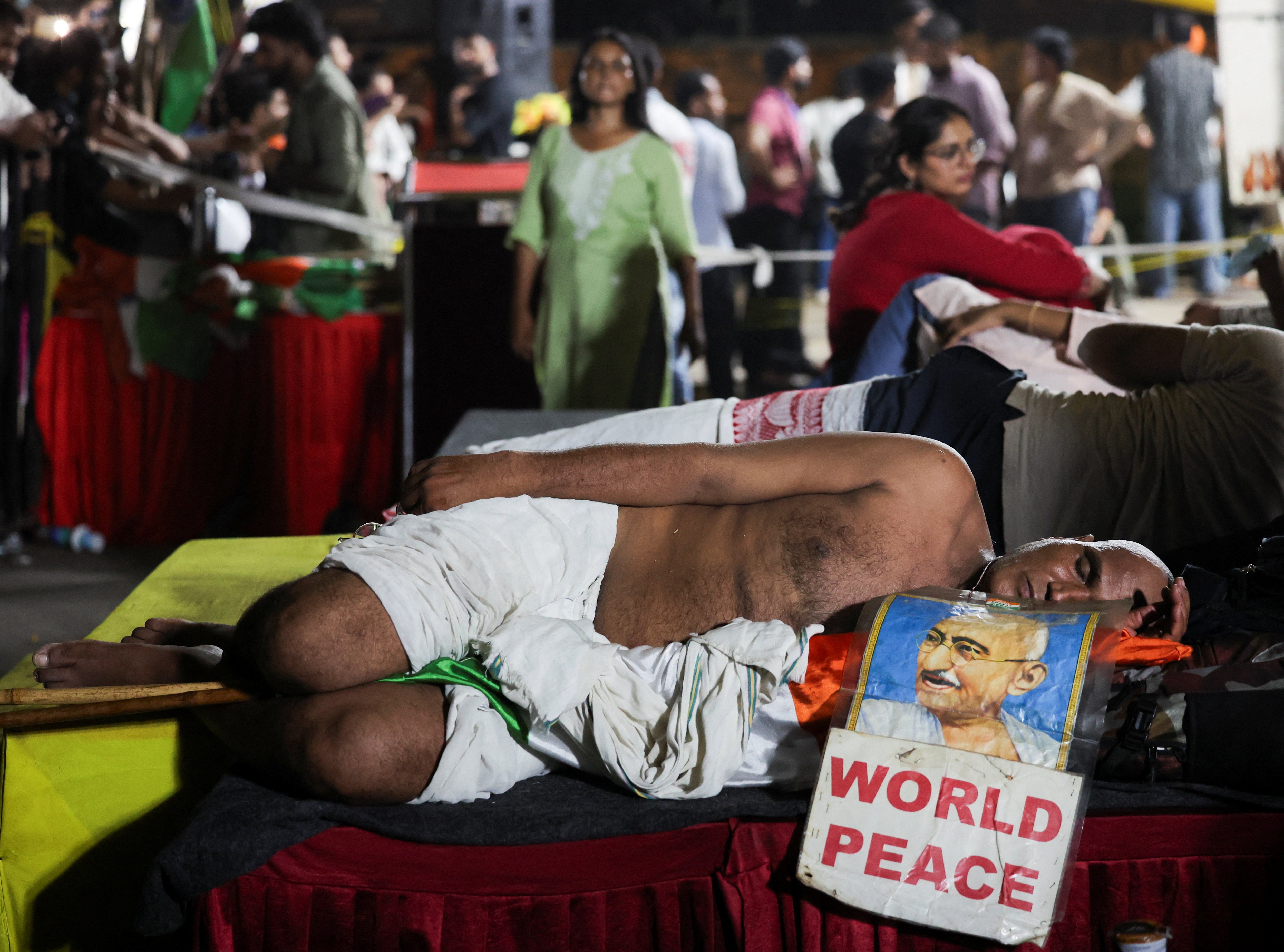 A supporter of the Cockroach Janta Party dressed as MK Gandhi sleeps at a protest site