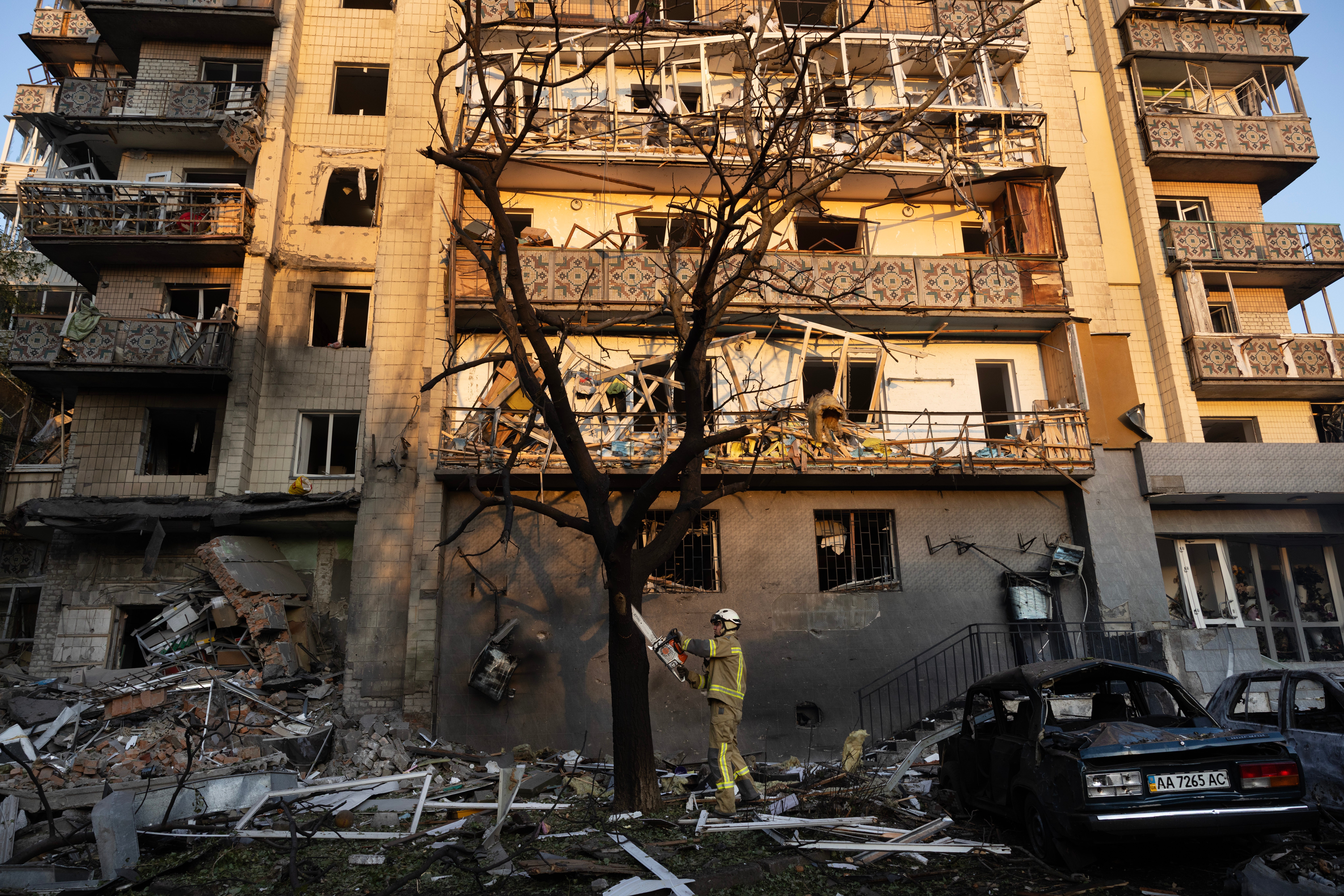A firefighter cuts a tree after a large-scale attack overnight that left at least one person dead and thirteen injured on July 19, 2026 in Kyiv, Ukraine. Kyiv was hit with about 40 Iskander-M and hypersonic Zircon missiles. (Getty)