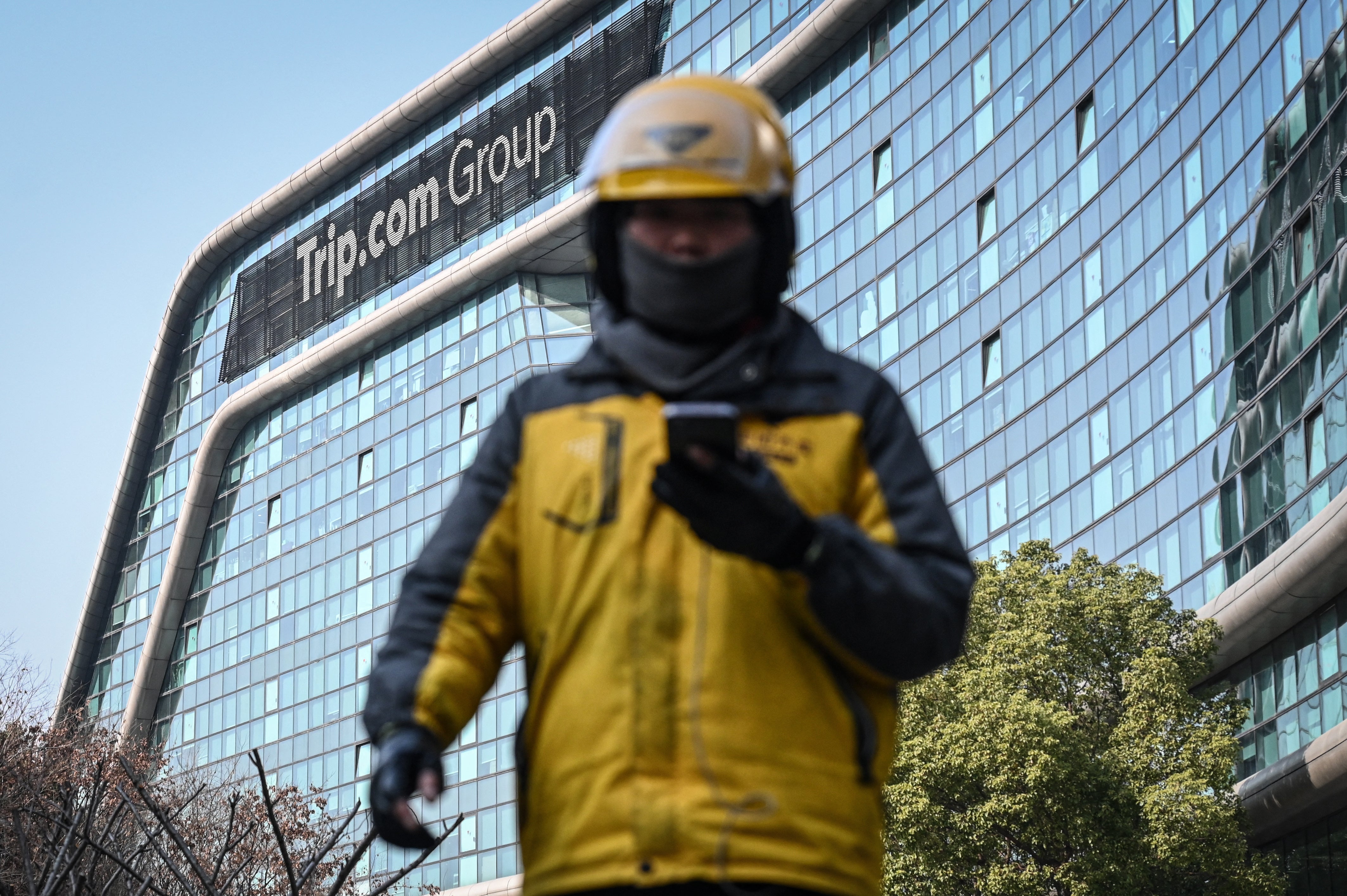 A food delivery driver walks past the headquarters of the travel agency Trip Group in Shanghai (AFP/Getty)