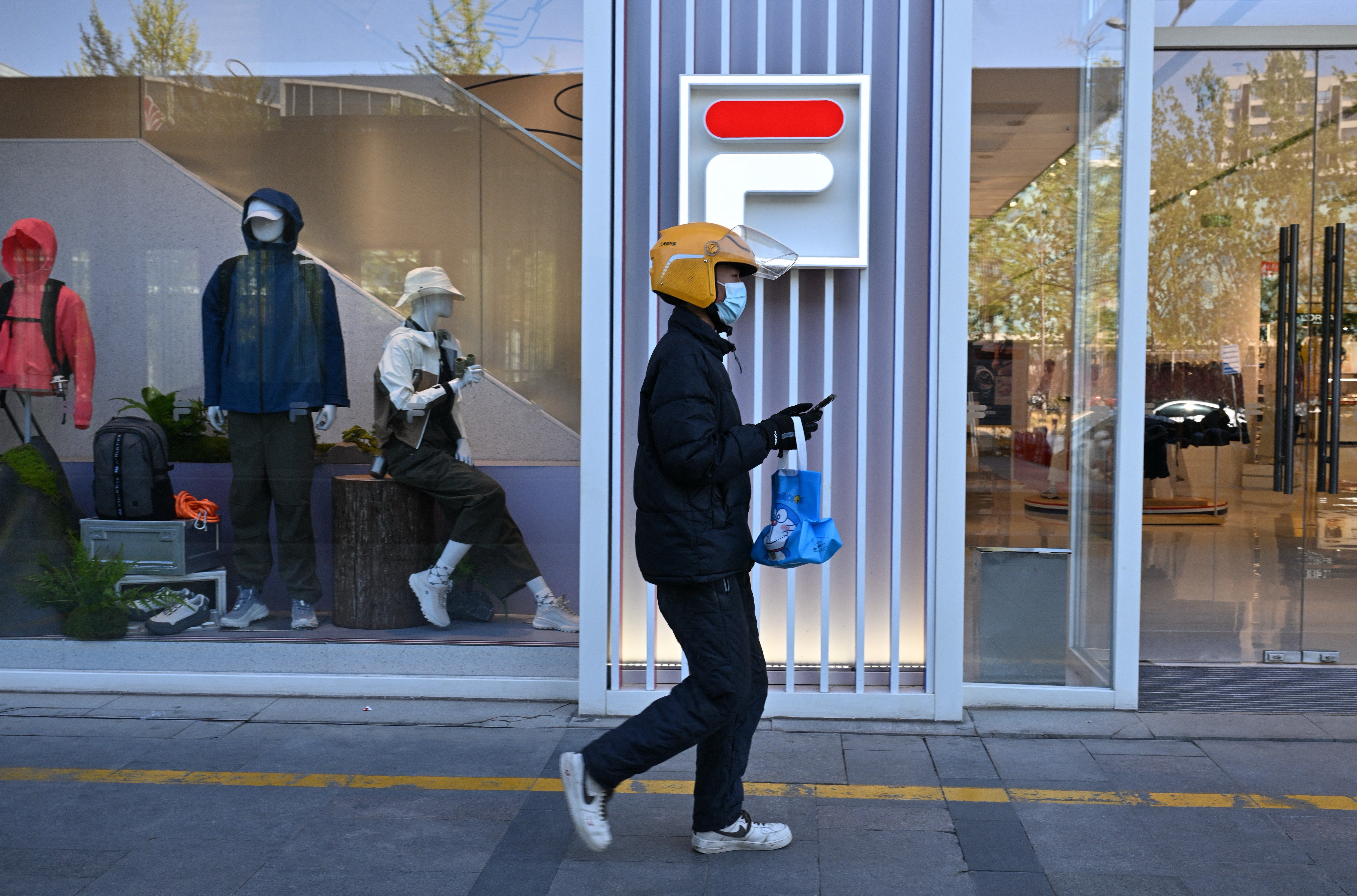 A food delivery man walks past a Fila store at a shopping centre in Beijing (AFP/Getty)