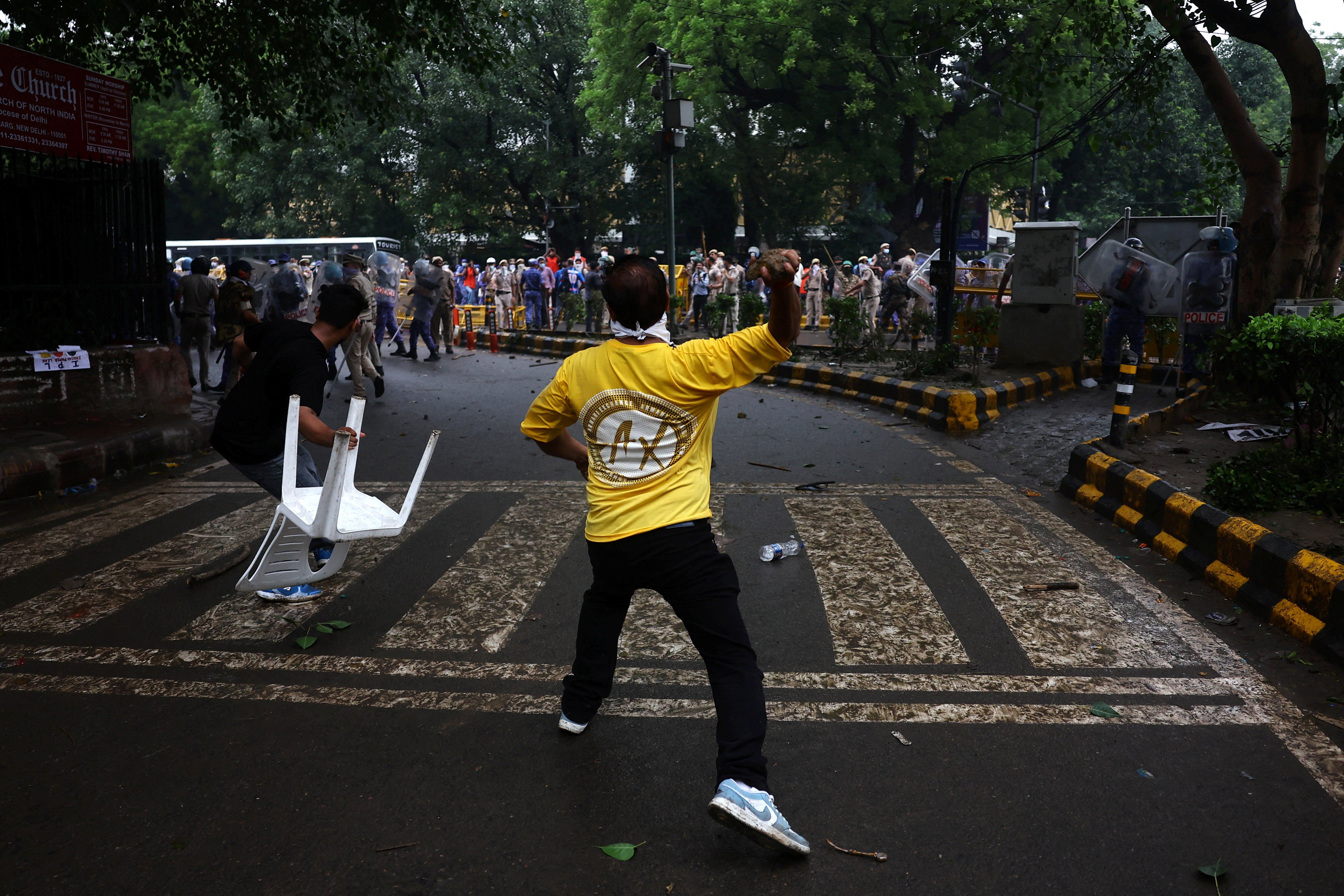 Demonstrators hurl a stone and a chair towards police (Reuters)