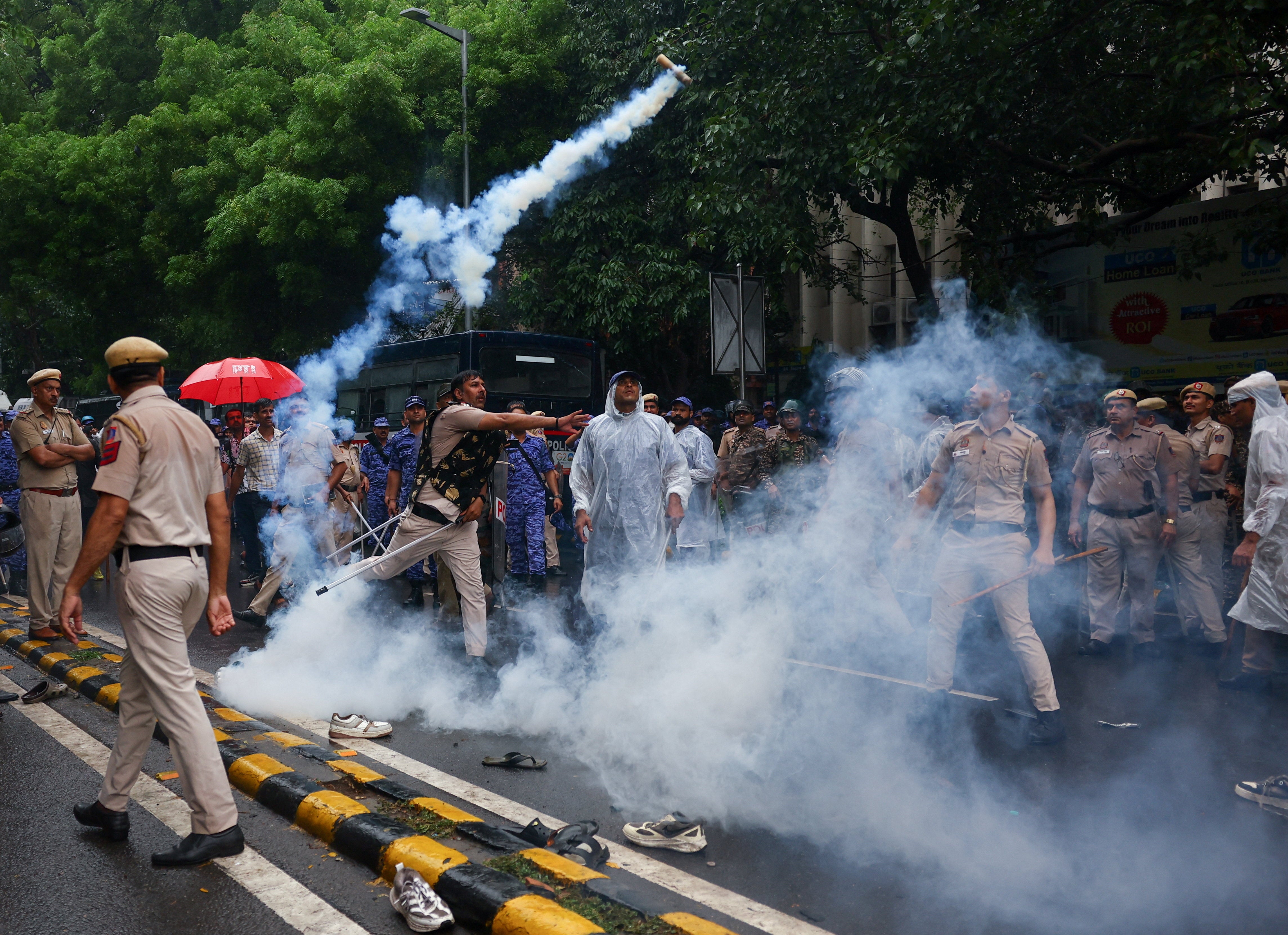 A police officer throws a tear gas canister towards protesters
