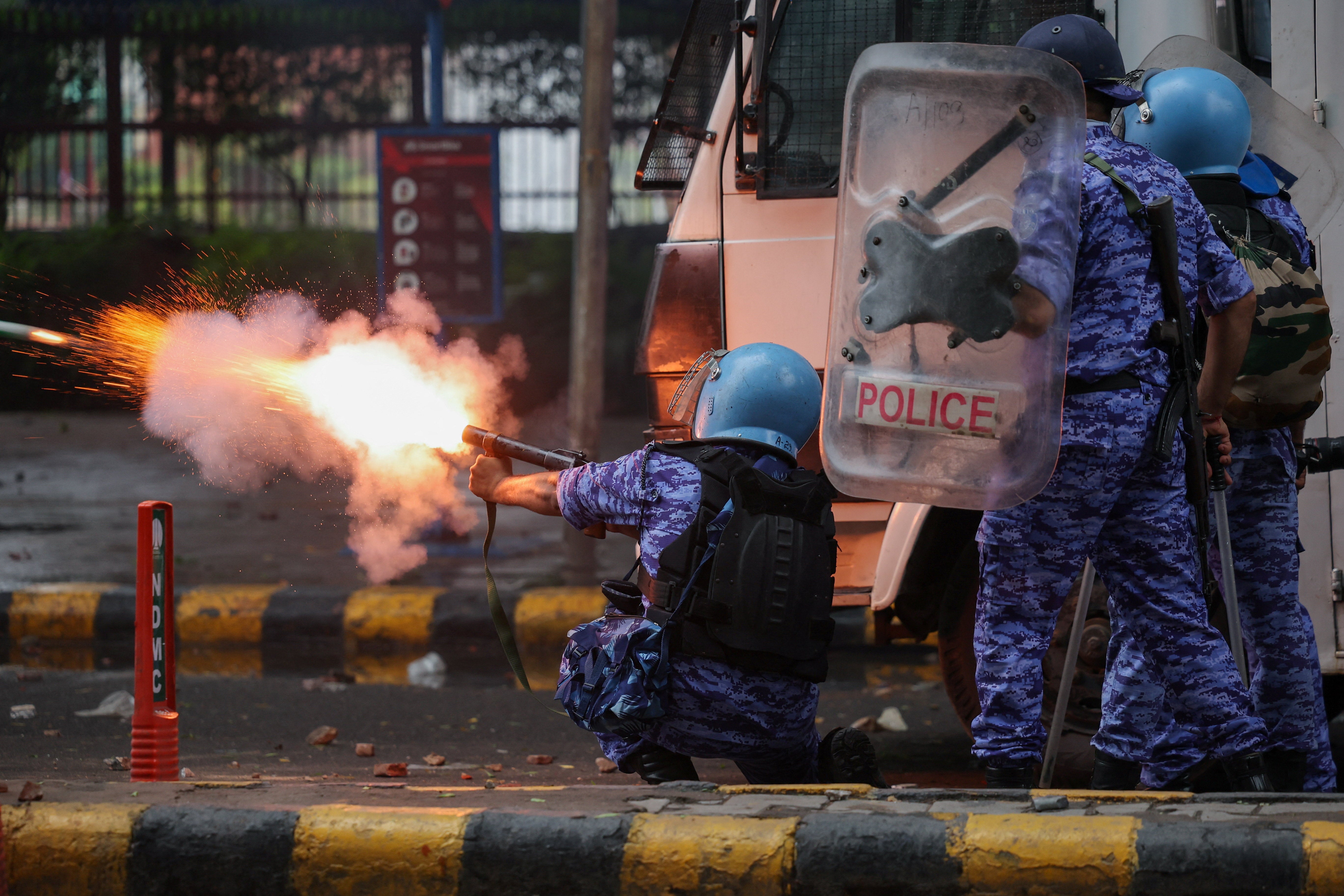 A member of the Rapid Action Force (RAF) fires a tear gas canister towards protesters