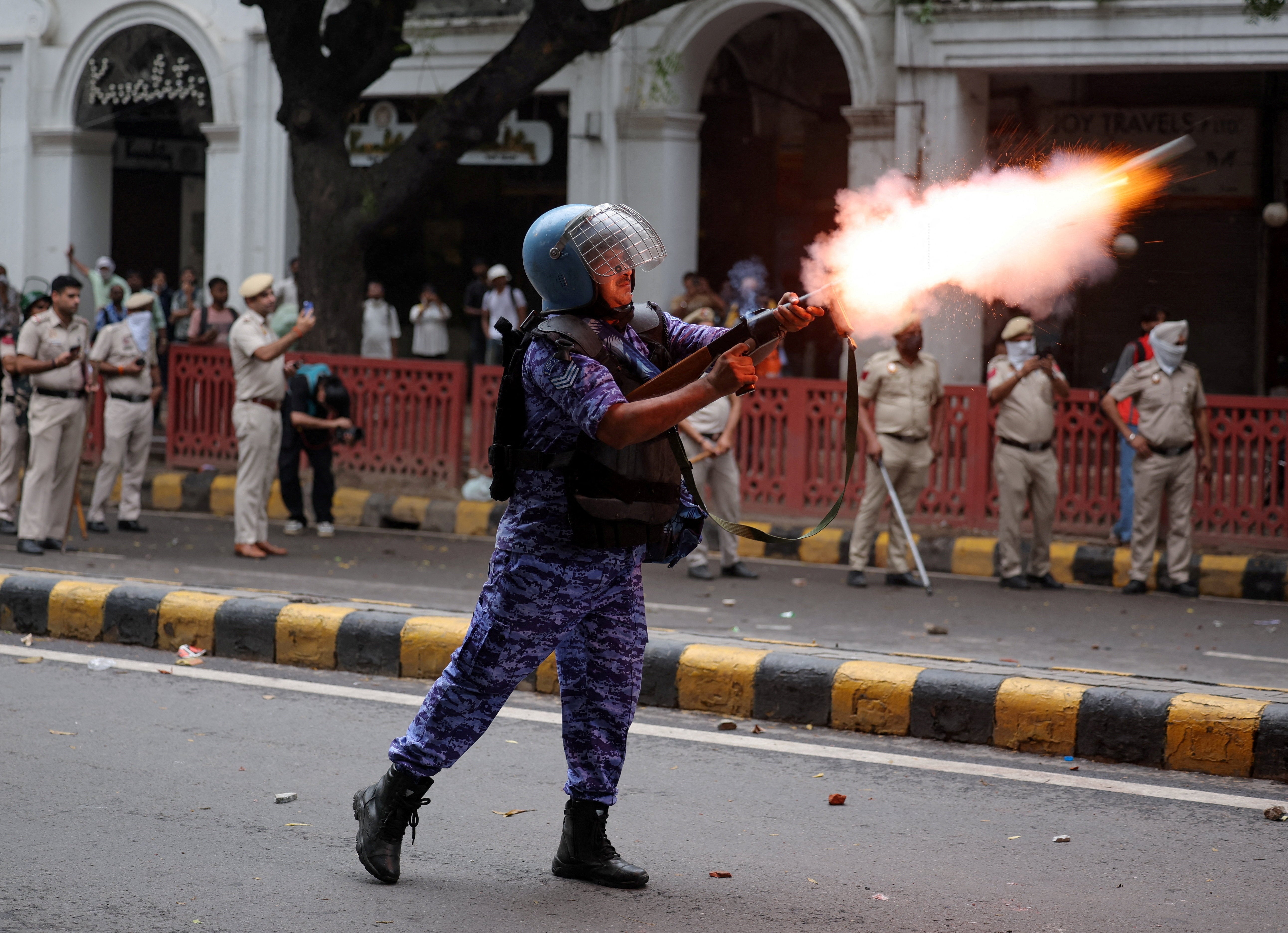 A member of the Rapid Action Force (RAF) fires a tear gas canister towards protesters