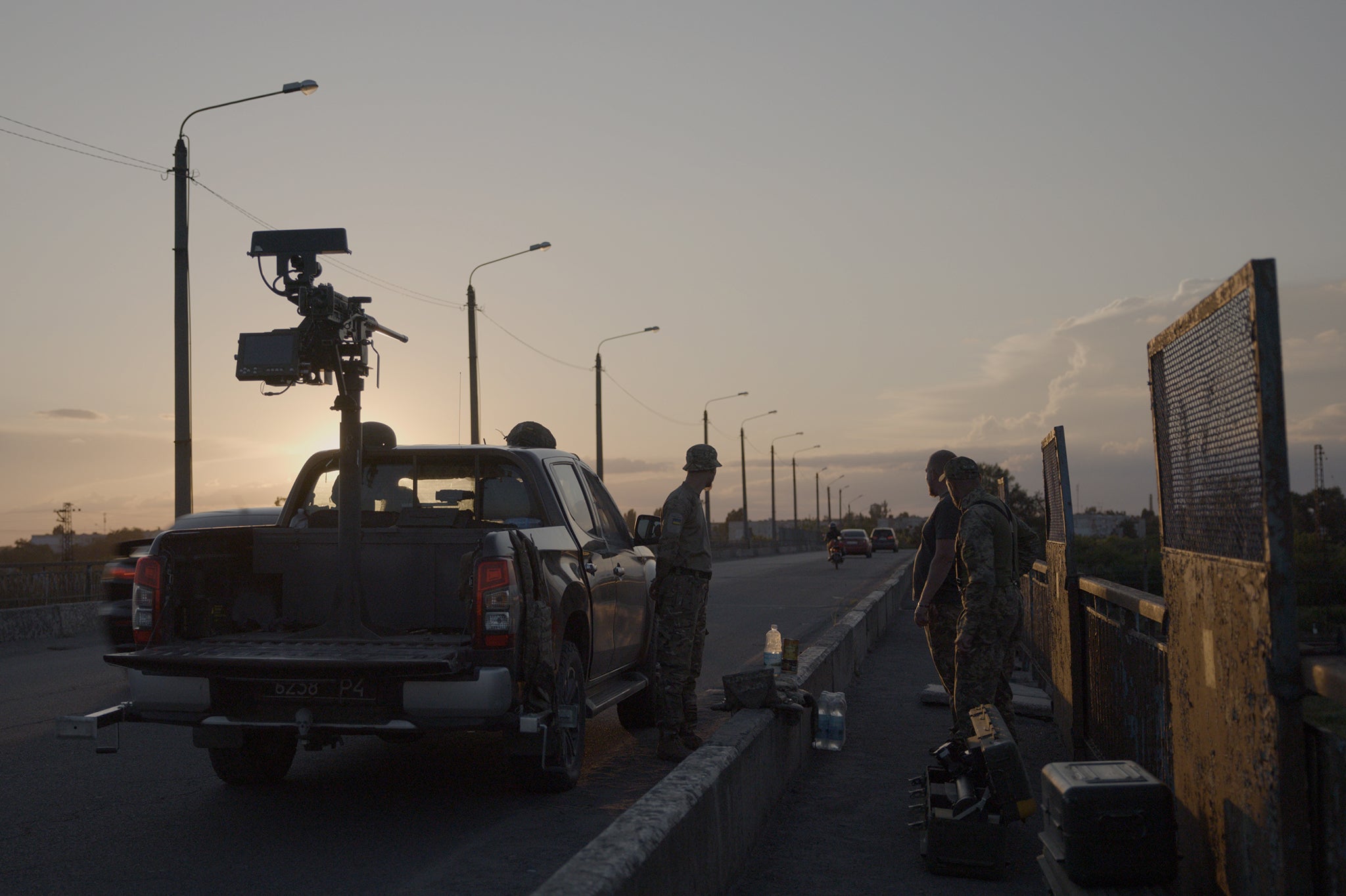 A flatbed truck carrying a large Browning machine gun, its barrel trained towards the sky, aiming at drones