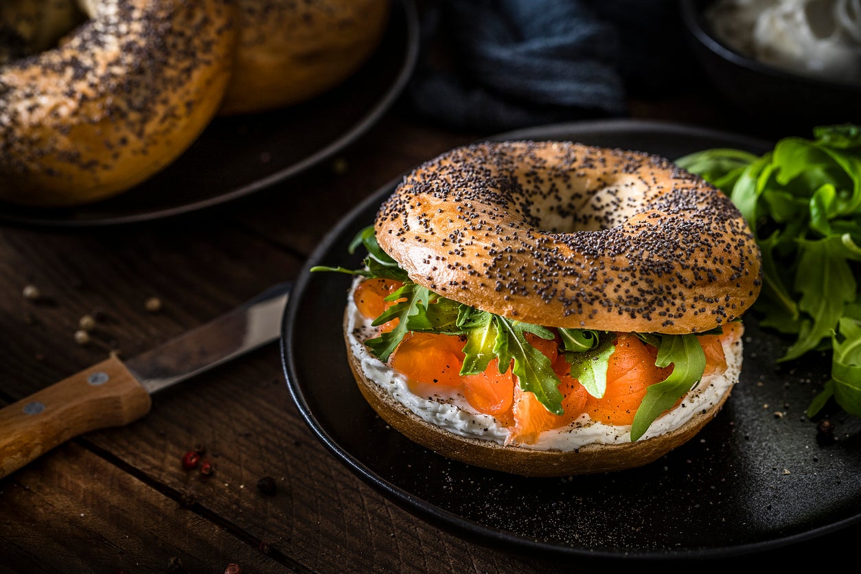 Whether it’s a classic ‘schmear’ of cream cheese, a more adventurous flavoured spread, or an elaborate stack piled high with fish, tomato, cucumber, and red onions, the bagel offers endless customisation (Getty Images)