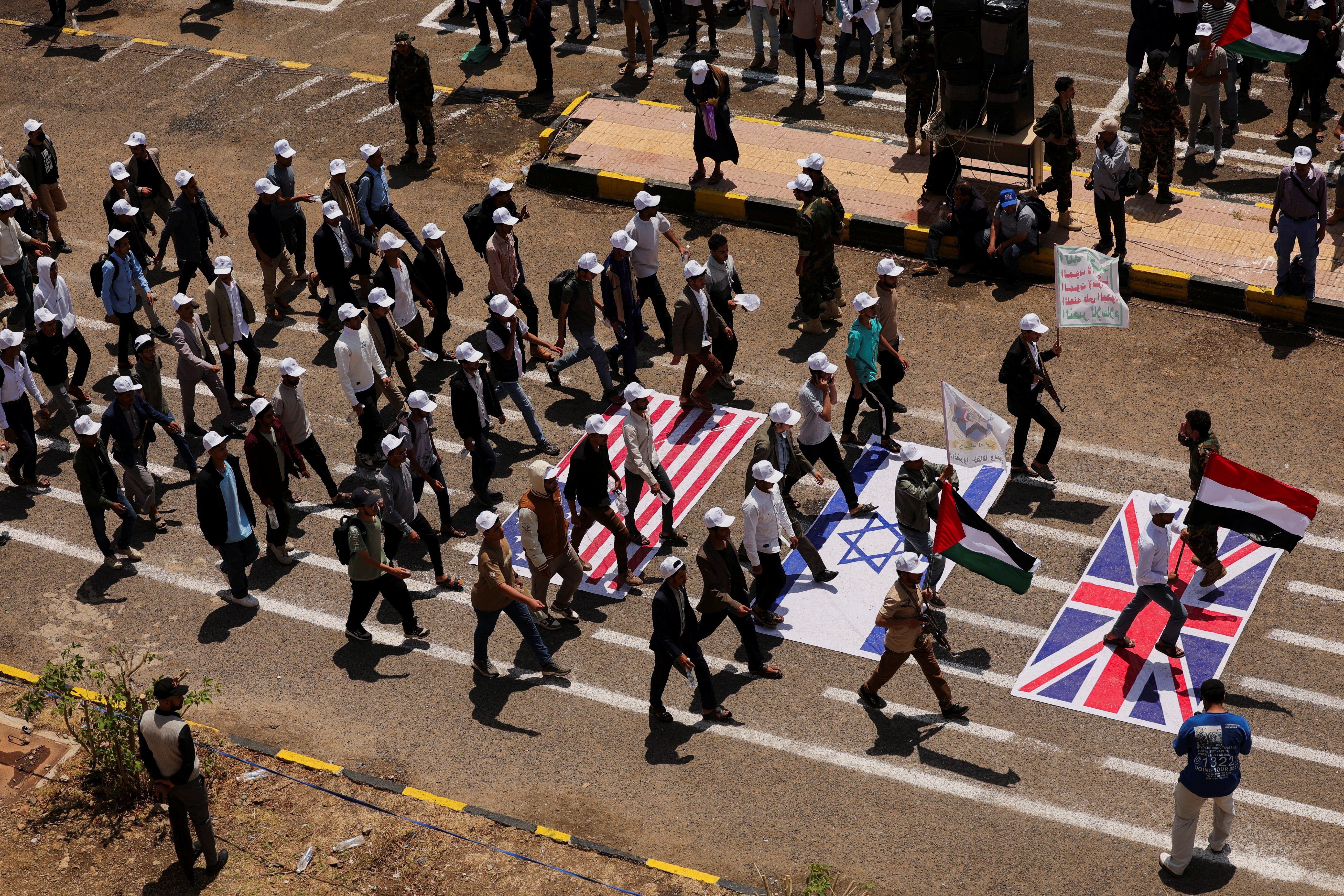 Students walk on U.S., Israeli and U.K. flags as they parade at Sanaa University campus to show support for the Houthis amid an escalation with Saudi Arabi (Reuters)