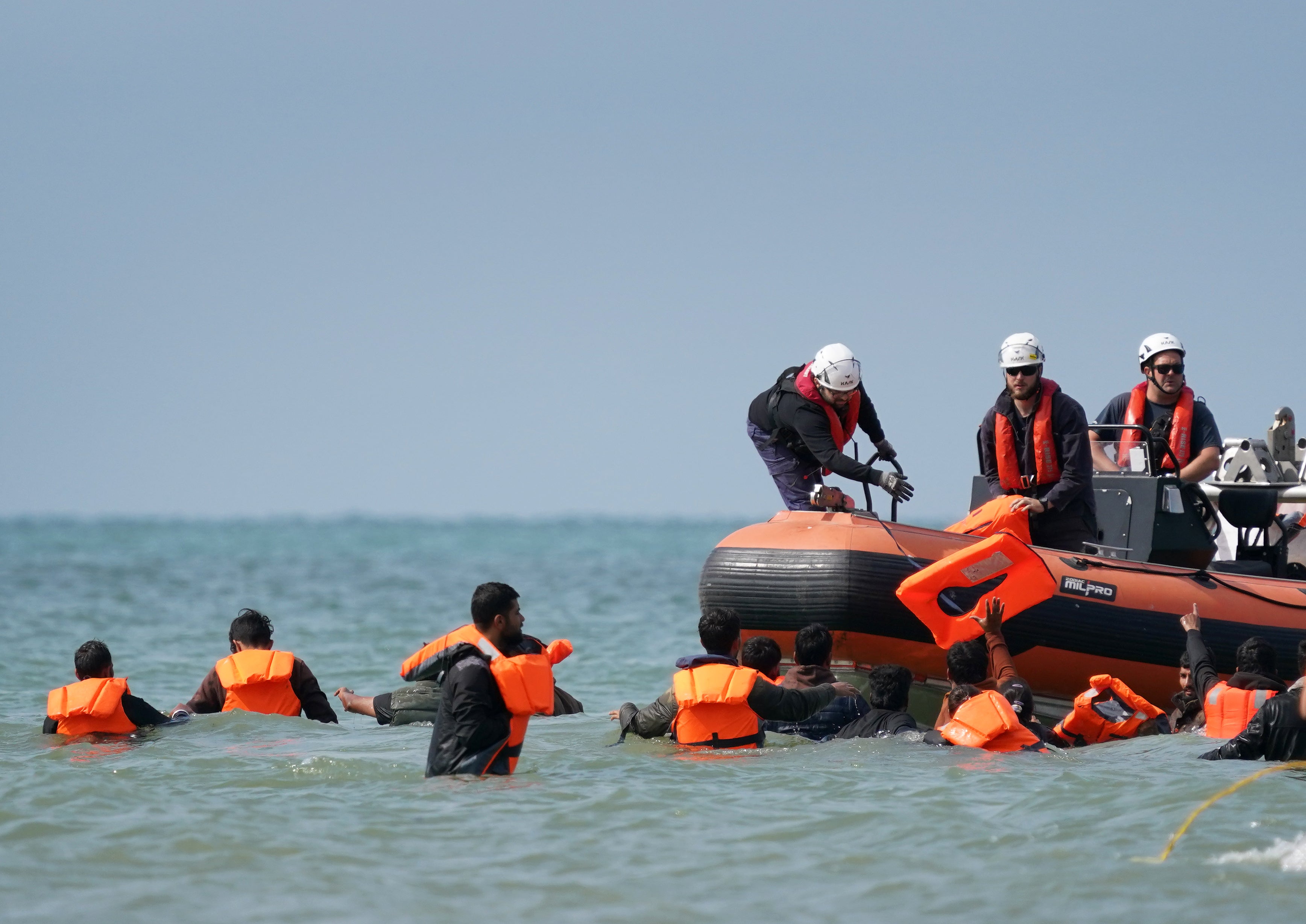 People thought to be migrants are handed life vests by French rescuers as they wade through the sea to board a small boat off the coast of Equihen-Plage (Gareth Fuller/PA)