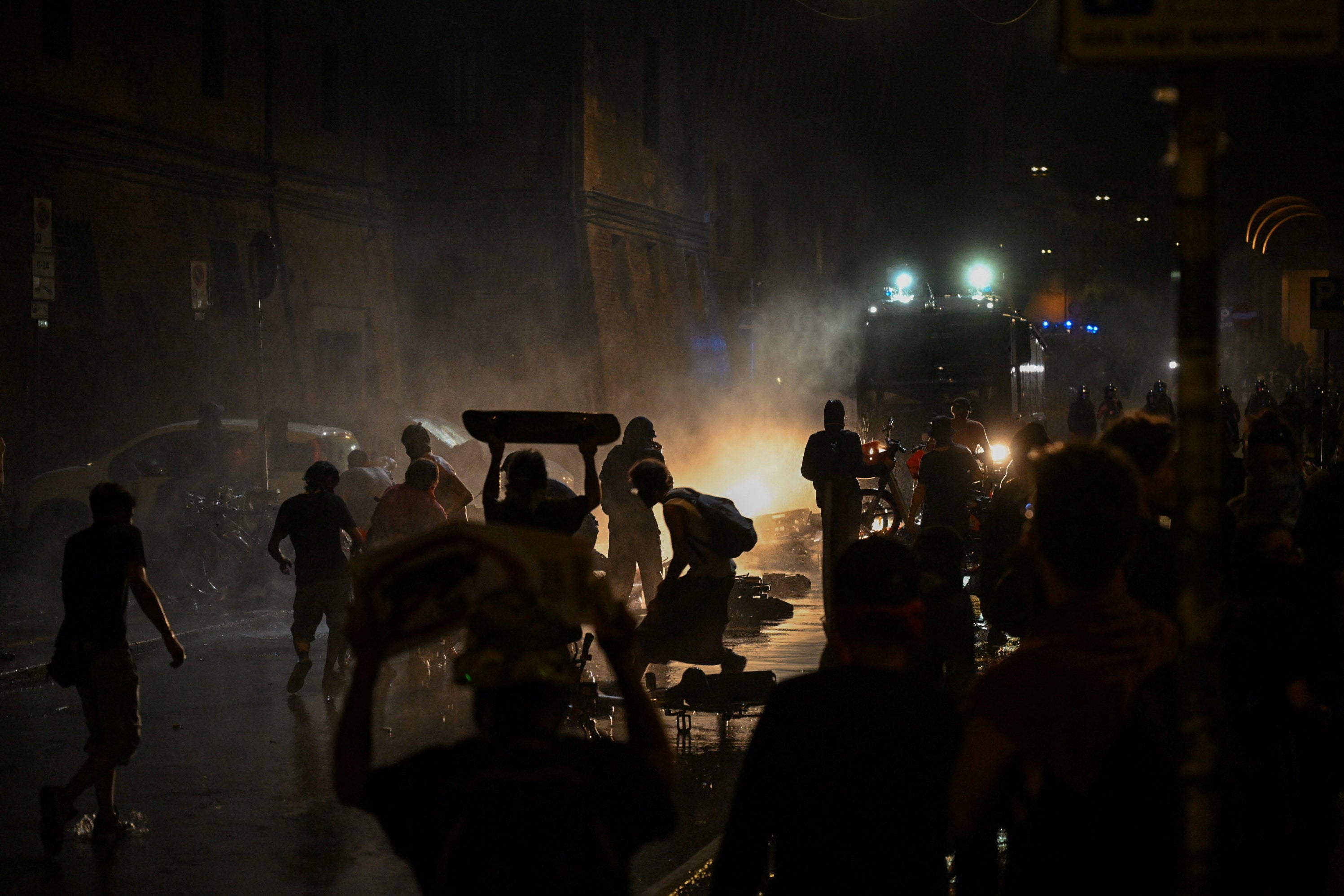 Protesters confront police amid smoke as a police vehicle moves along a street during a demonstration following the death of Abderrahim Fakir, in Bologna, Italy, July 20, 2026.