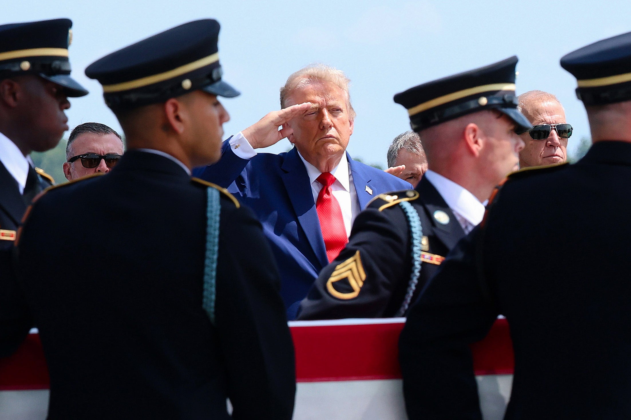 Donald Trump (C) salutes as members of a US Army carry team as they transfer the remains of the killed soldiers (Getty)