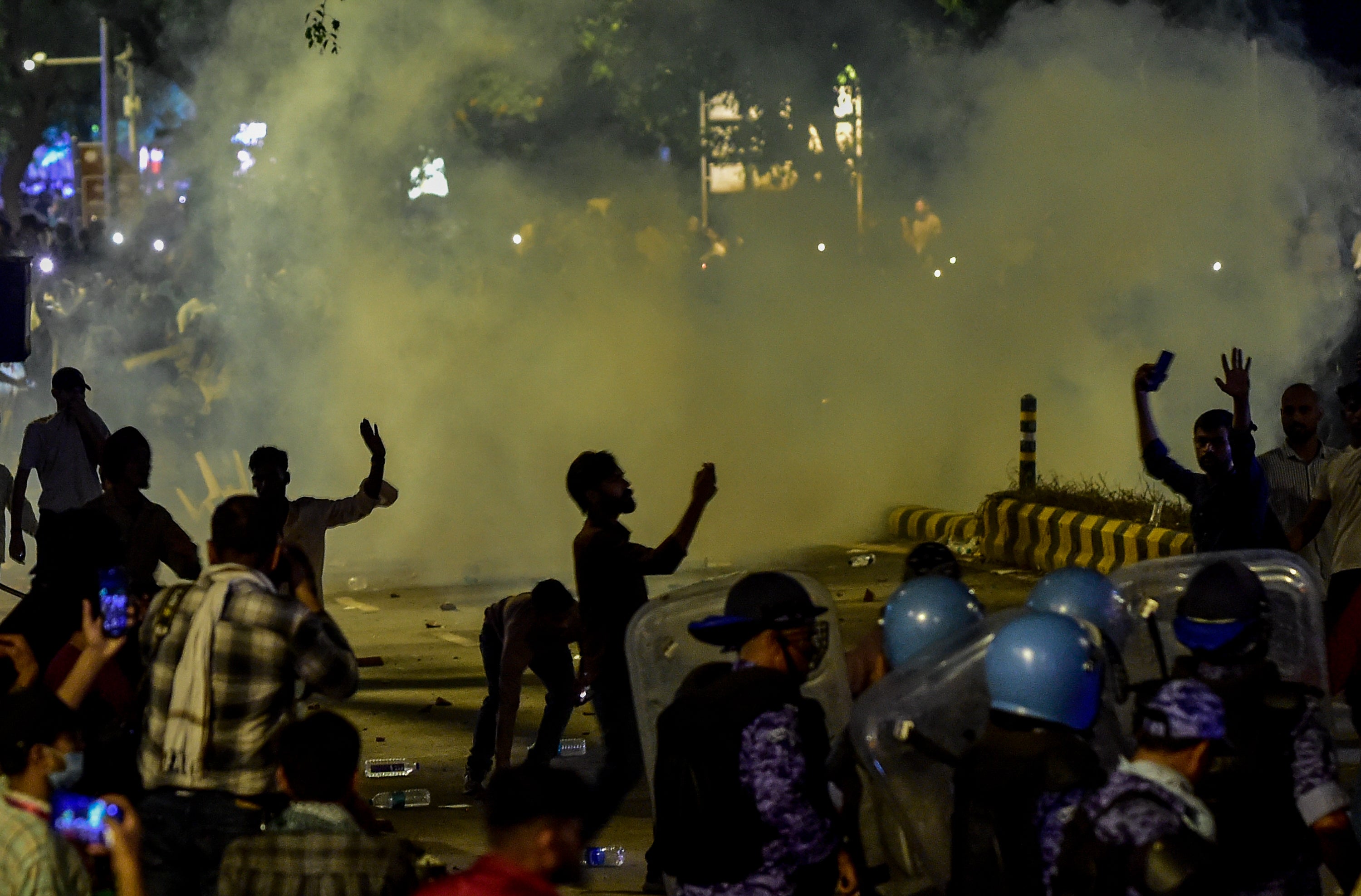 Tear gas fills the air as police officers in riot gear face protesters during a demonstration led by the Cockroach Janta Party (CJP) (Getty)