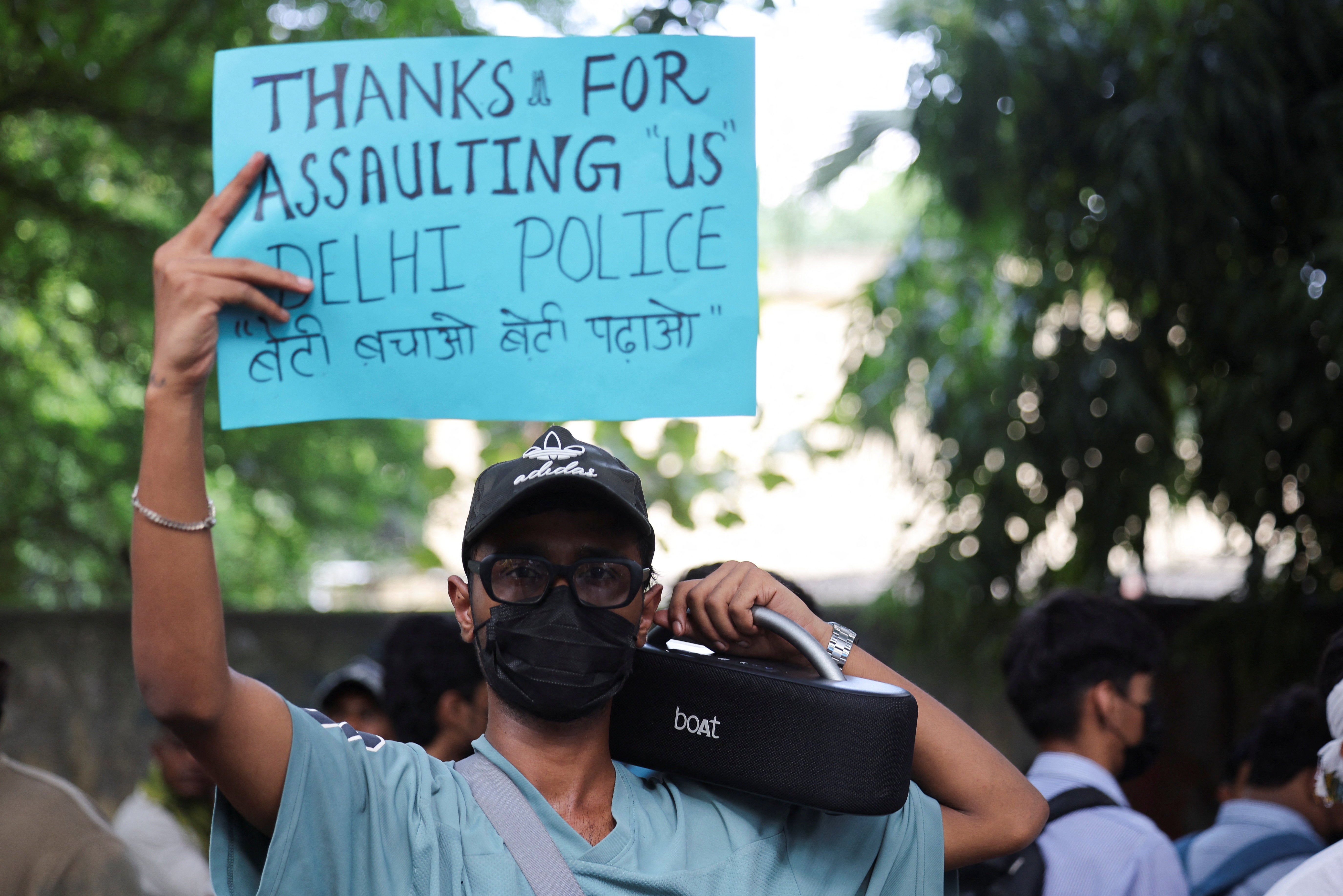 A protester holds a placard mocking police for assaulting young protesters demanding the resignation of education minister Dharmendra Pradhan