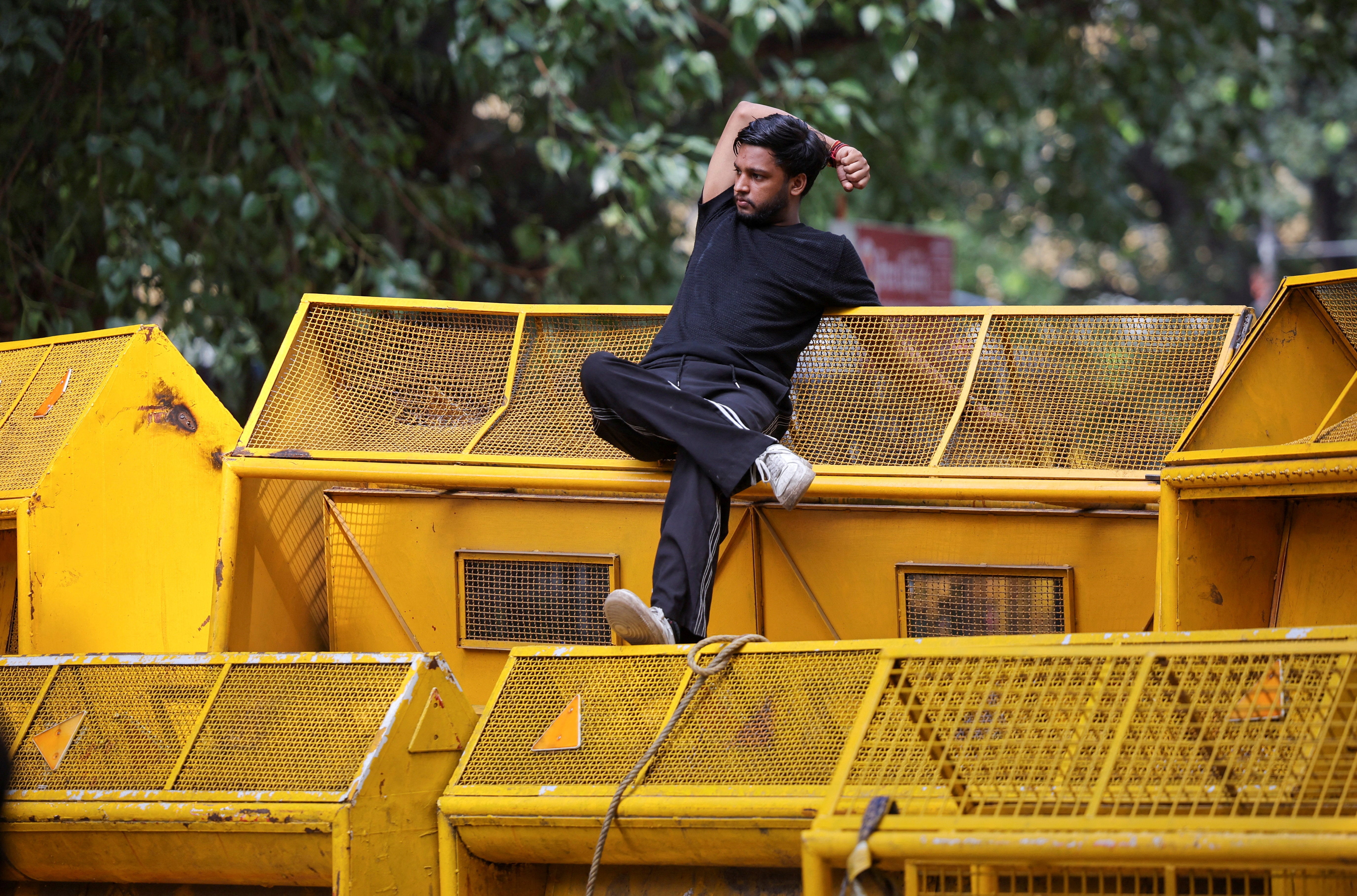 A supporter of India's Cockroach Janata Party rests on a police barricade during protests in Delhi