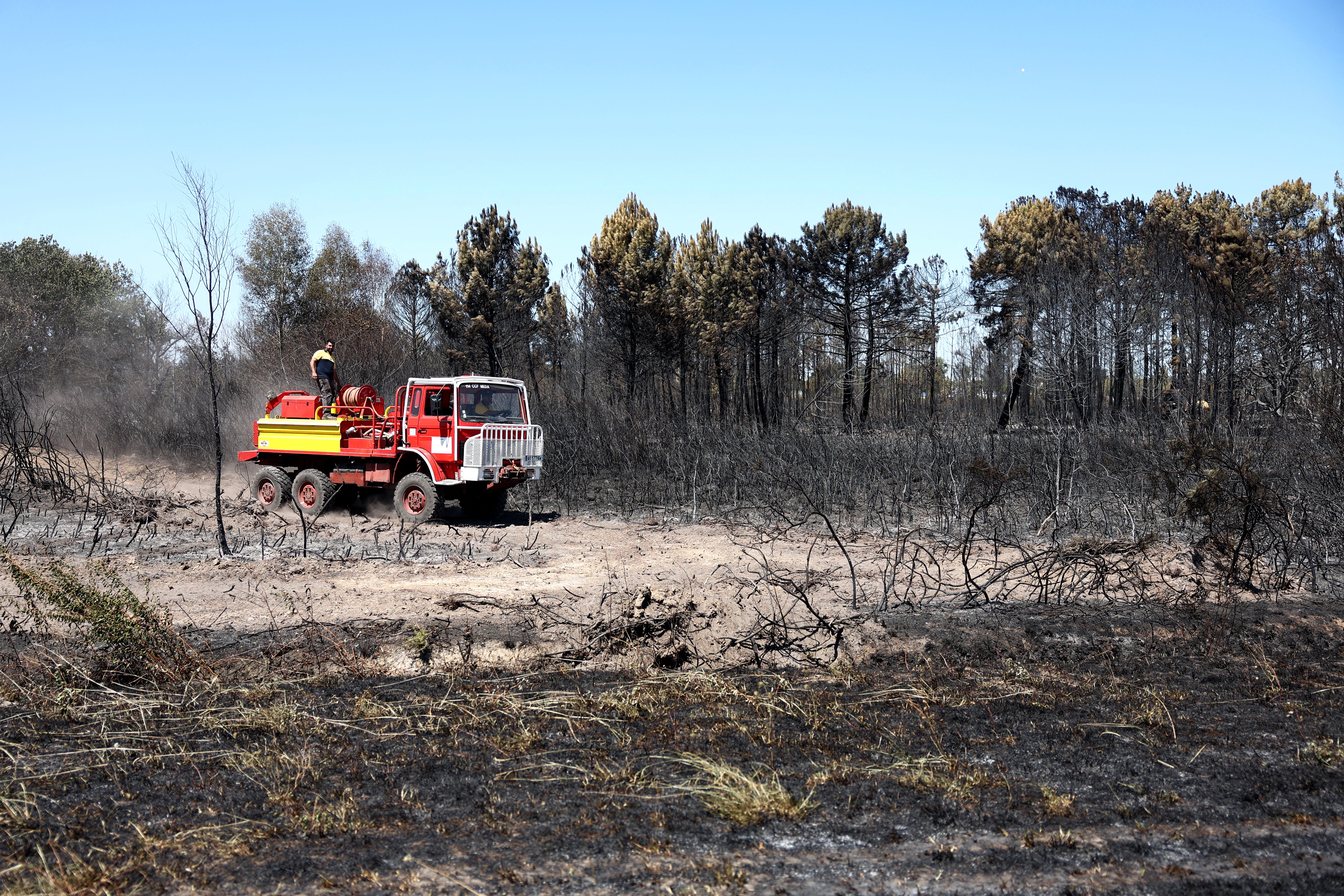Locals drive an old fire truck at the site where a wildfire broke out on July 21