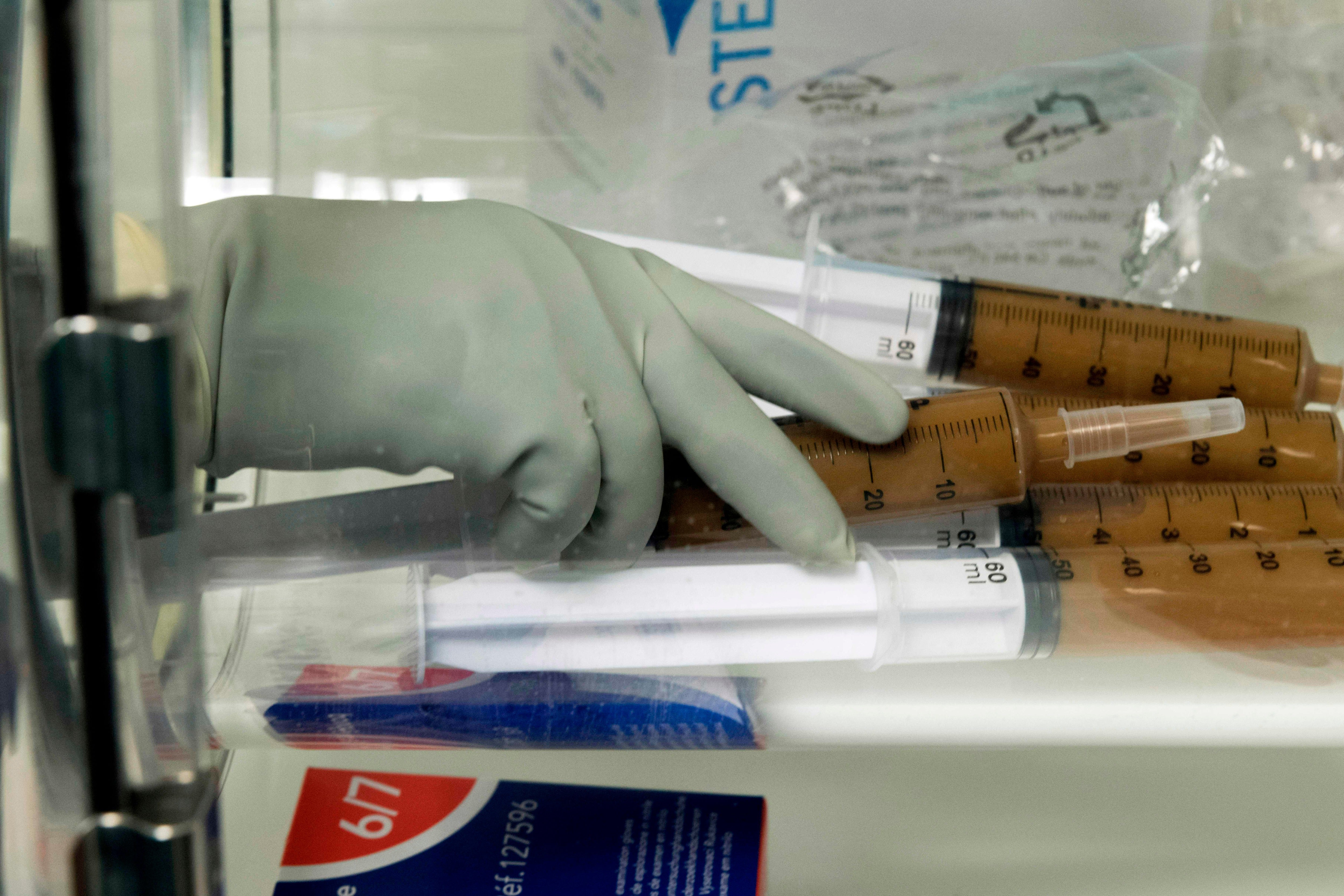 Laboratory technicians at the Centre Hospitalier Universitaire (CHU) prepare syringes with stool mixed in a solution to treat patients with serious infections of the colon by faecal microbiota transplantation (FMT)