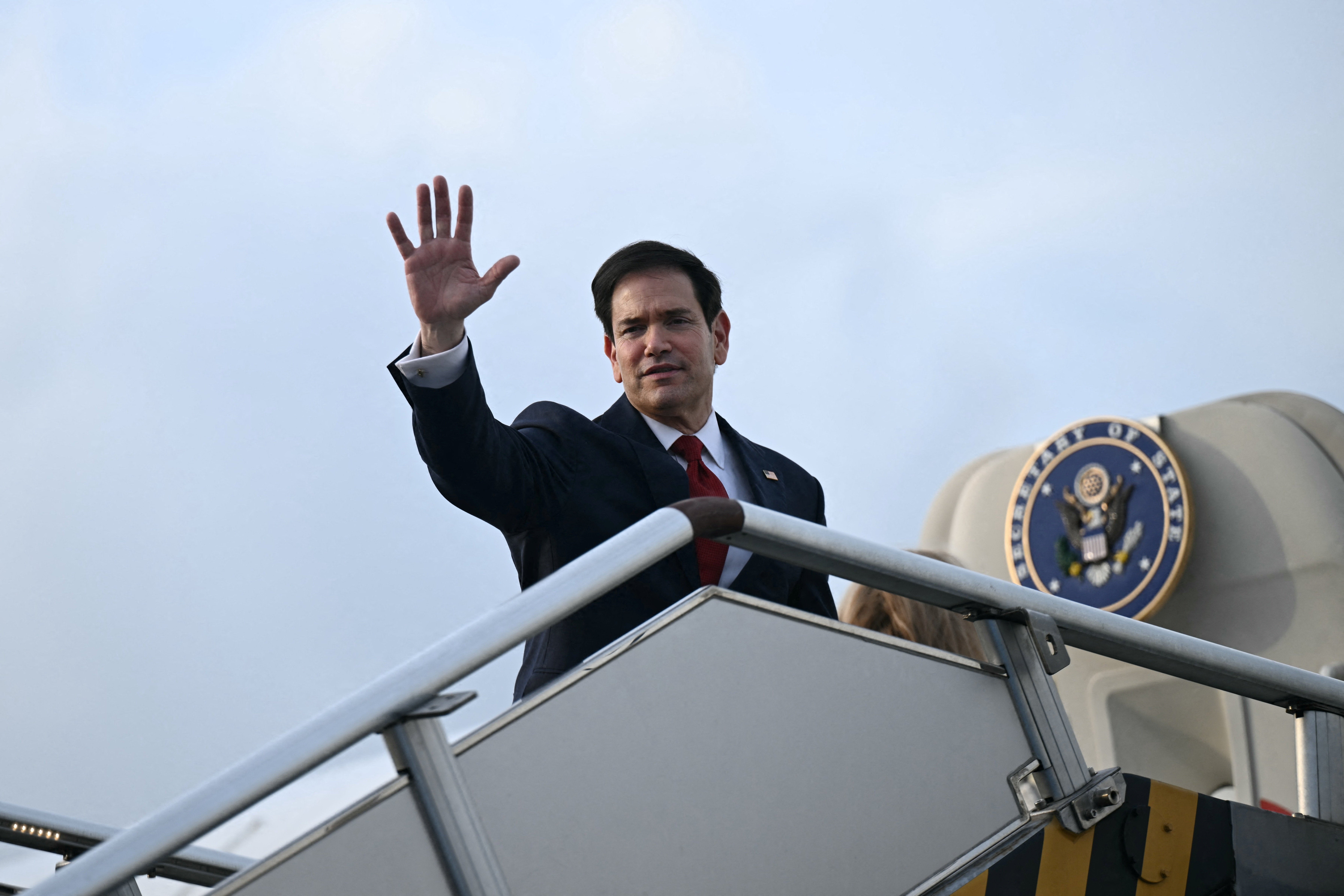 US Secretary of State Marco Rubio waves from the top of the steps to his plane as he departs at Ninoy Aquino International Airport in Metro Manila