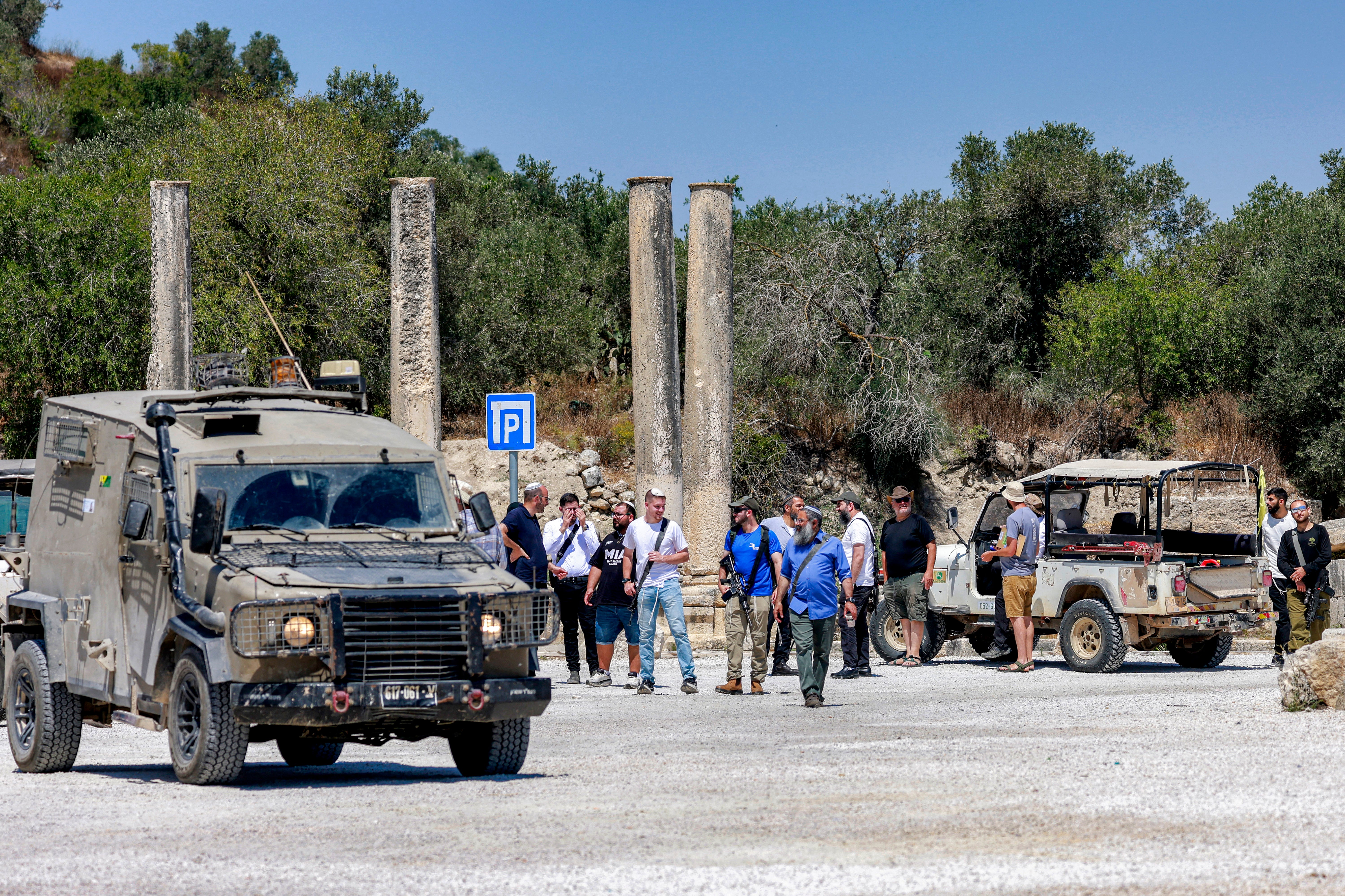 Israeli settlers are pictured near Israeli military vehicles during an official visit by a group of foreign diplomats accredited by the Palestinian Authority at the archaeological site of Sebastia, north of Nablus in the occupied West Bank, on June 29, 2026
