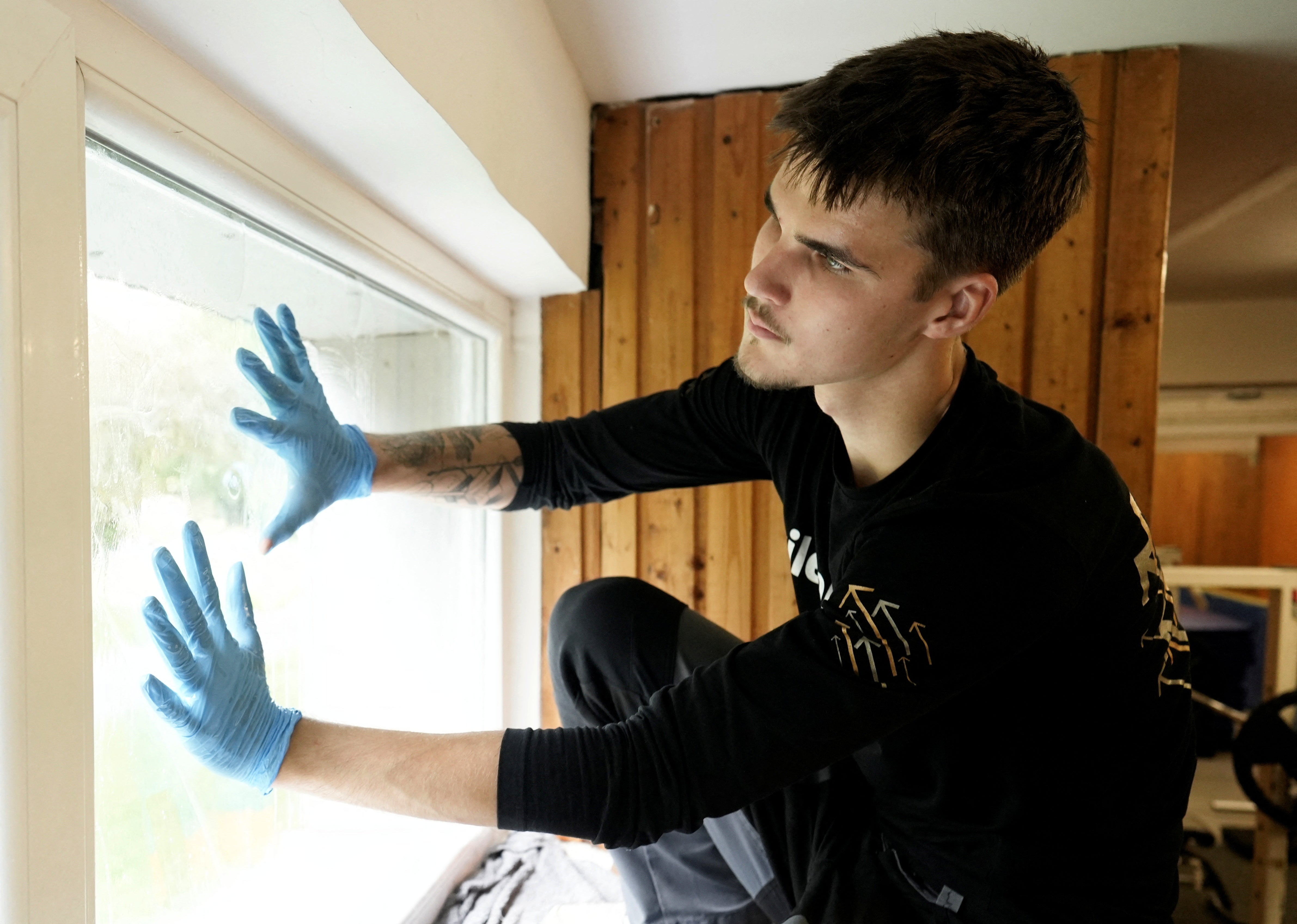 Rasmus Maivel installs plastic film to protect a window of an emergency shelter at an Estonian school (Reuters)