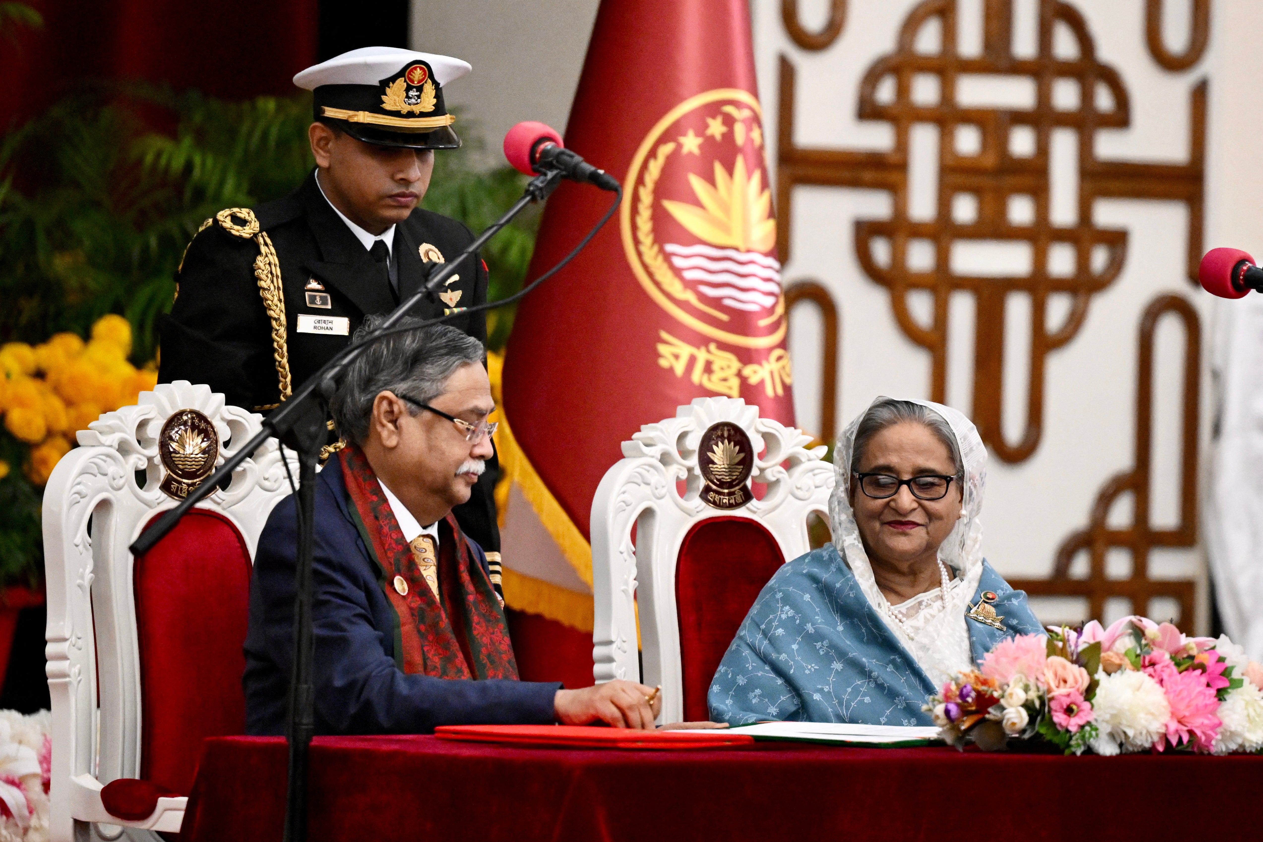 File. Bangladesh president Mohammed Shahabuddin (C) watches as prime minister Sheikh Hasina (R) signs documents after being sworn in for her fifth term at the Presidential Palace in Dhaka on 11 January 2024