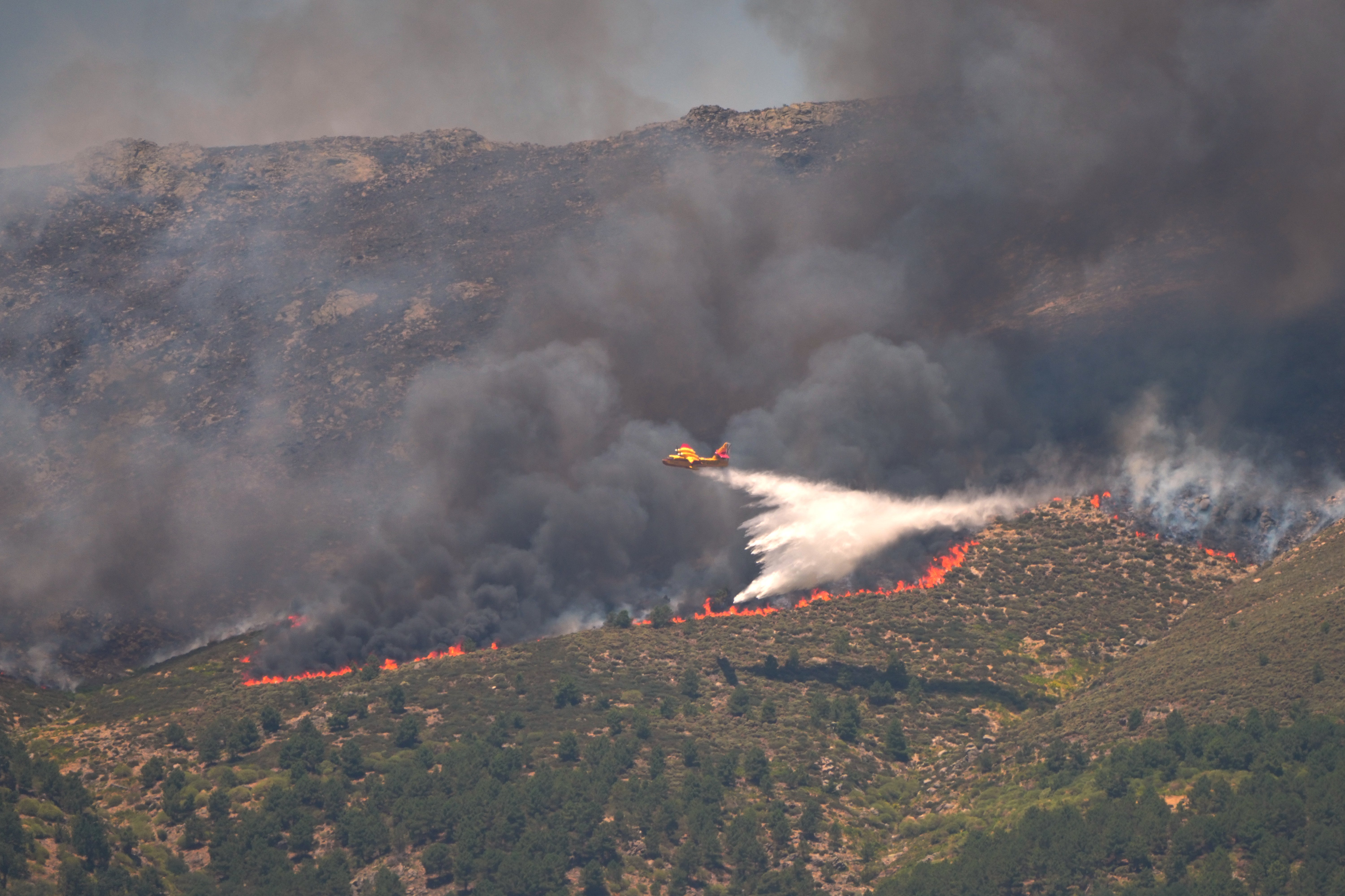 A seaplane drops water onto a wildfire near La Adrada, Ávila province