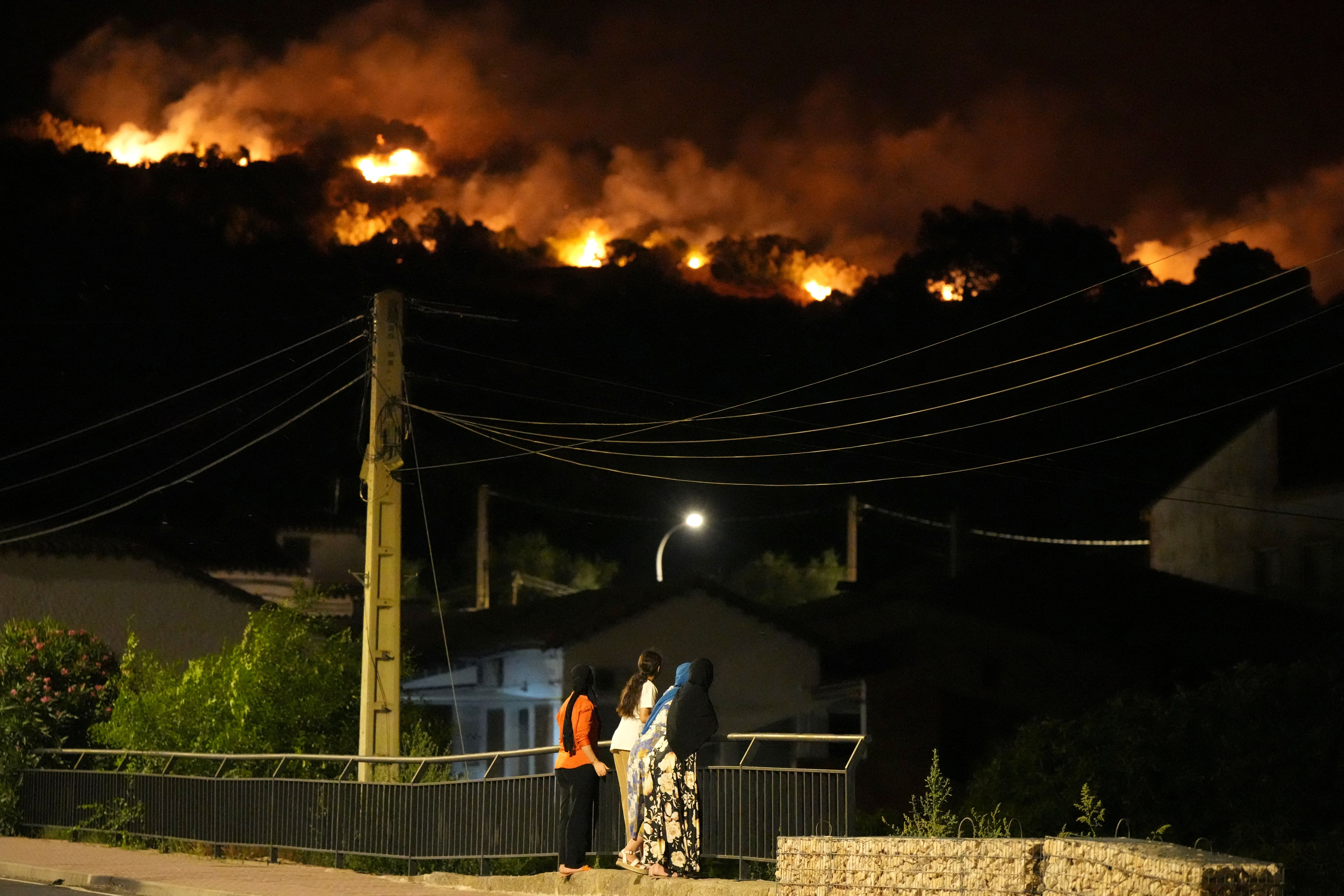 Residents watch the flames on hill crests as firefighters battle a wildfire in Cebreros area, near Avila (AFP/Getty)