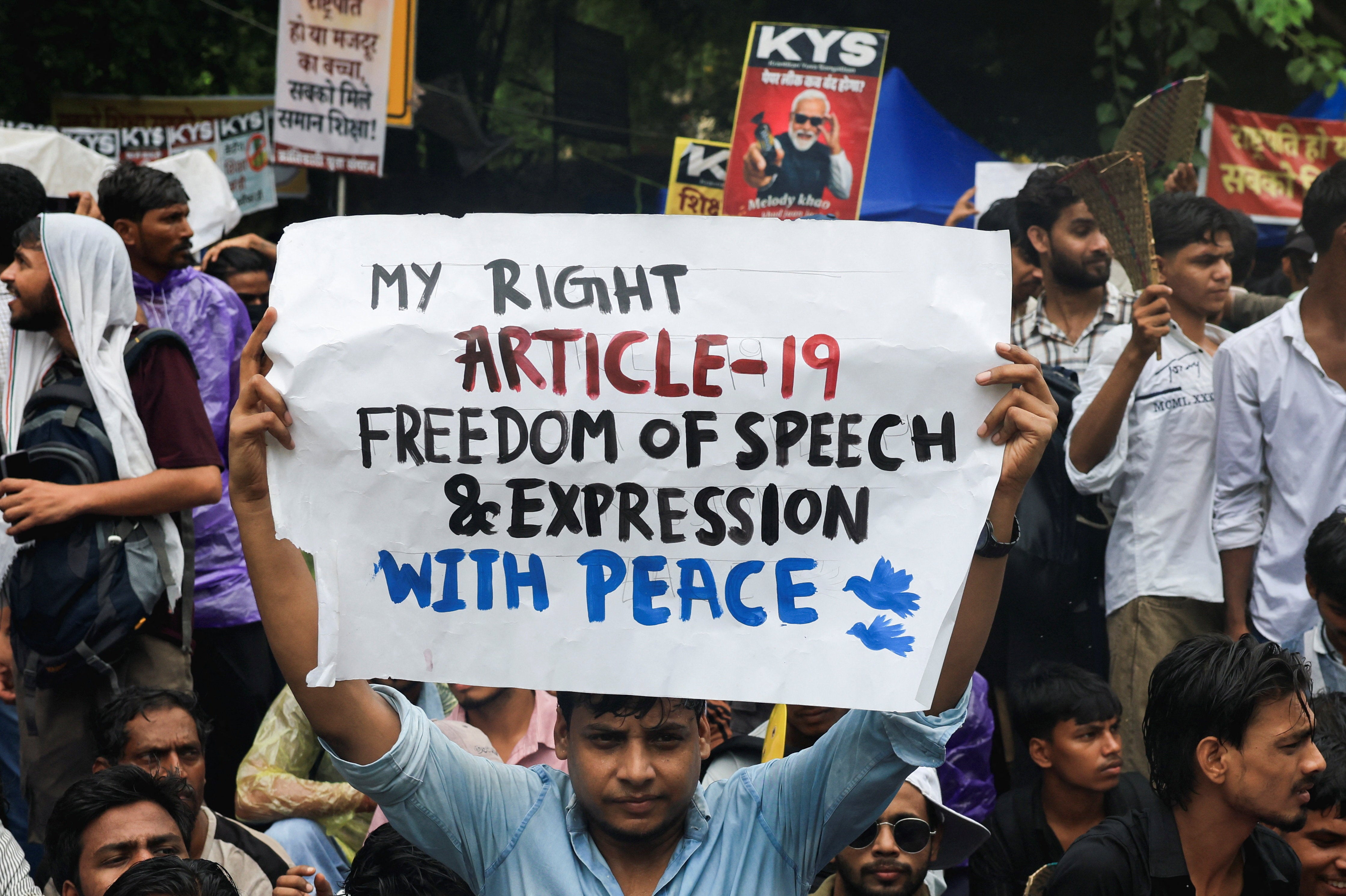 A protester holds a placard during an ongoing protest, days after thousands of protesters marched towards parliament demanding the resignation of Education Minister Dharmendra Pradhan