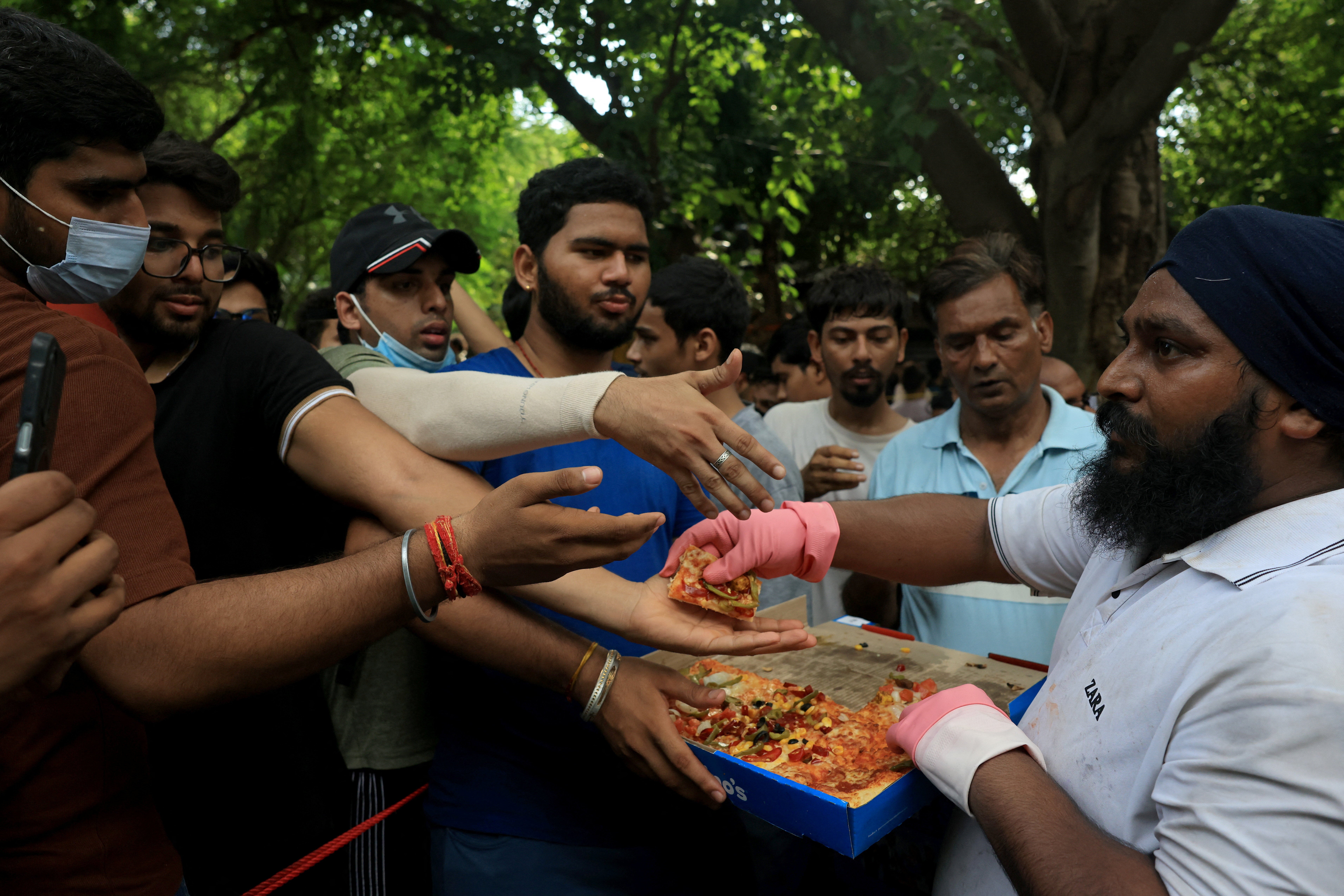 Supporters of India’s Cockroach Janata Party (CJP) queue up for free pizza sent by unknown supporters through food delivery apps