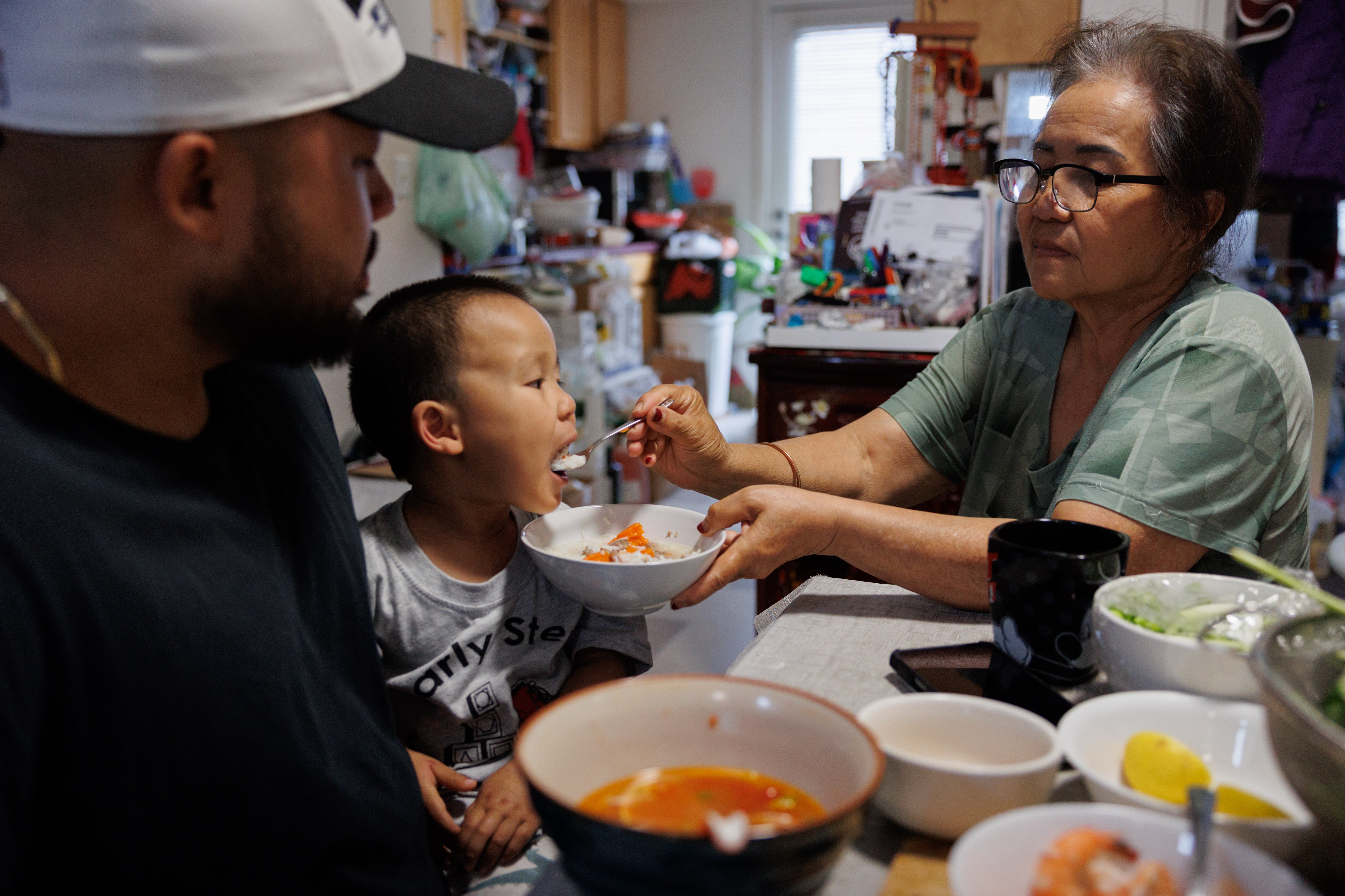 Lien Chang feeds her 2-year-old grandson, Cairo Miu, a bowl of rice next to his dad Jack Chang