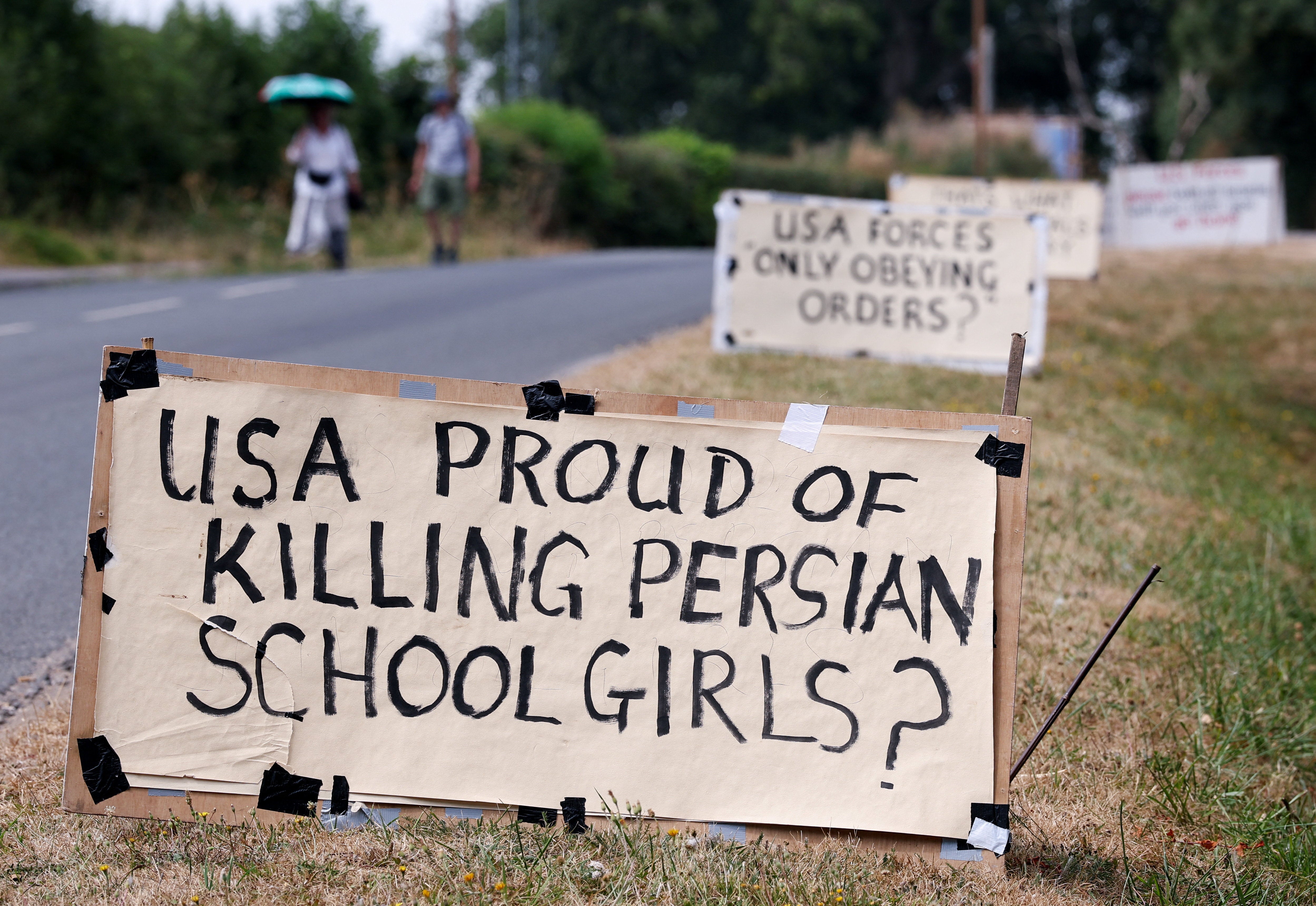 People walk next to placards on the roadside on the day of an anti-war demonstration outside the main gate of RAF Fairford airbase, which hosts U.S. Air Force (USAF) personnel (Reuters)