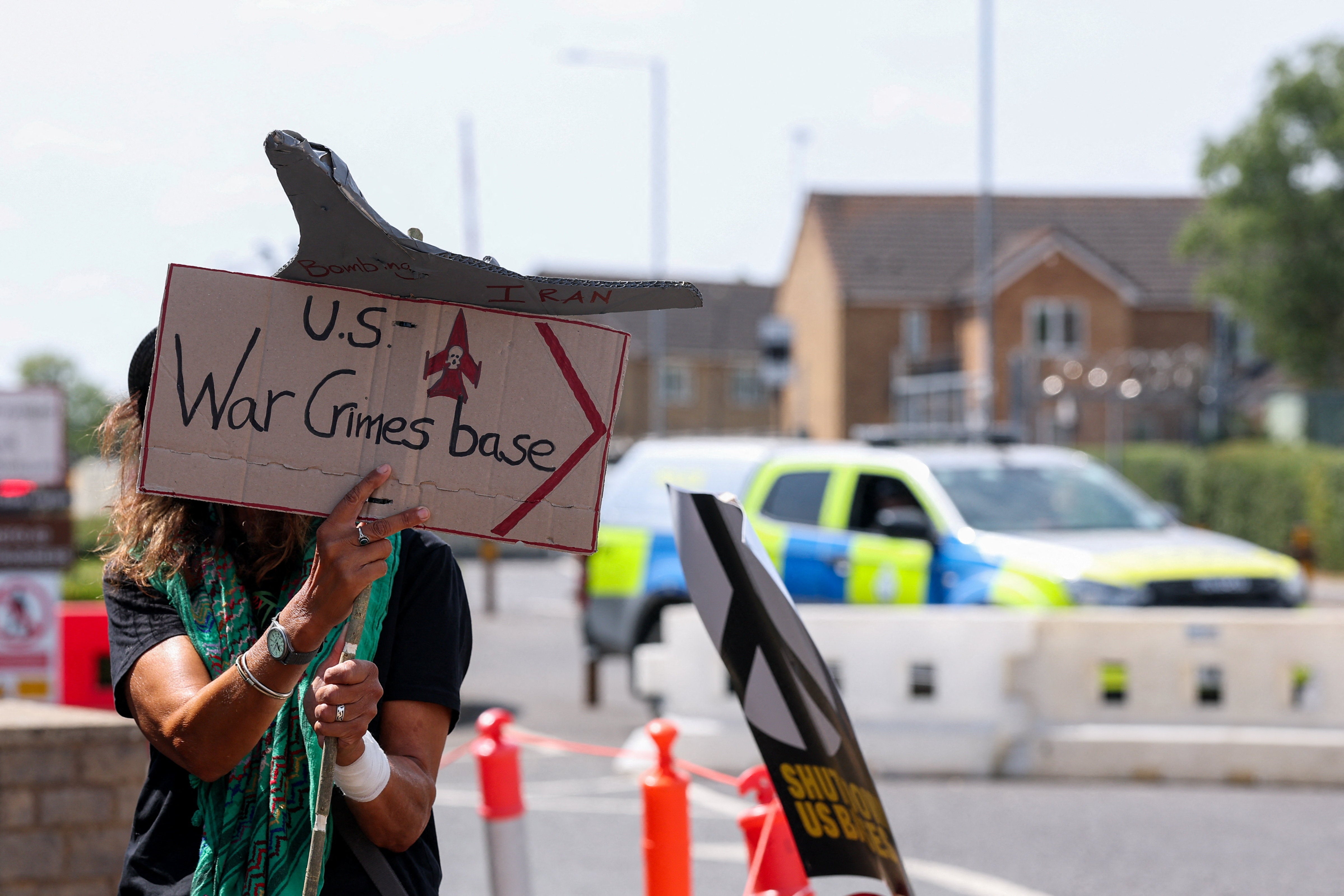 A protester stands near a police vehicle while attending an anti-war demonstration outside the main gate of RAF Fairford airbase, which hosts U.S. Air Force (USAF) personnel, after the British government said on Thursday that Britain's armed forces stand ready to defend the country and its military bases against any attack, in Fairford, Gloucestershire (Reuters)