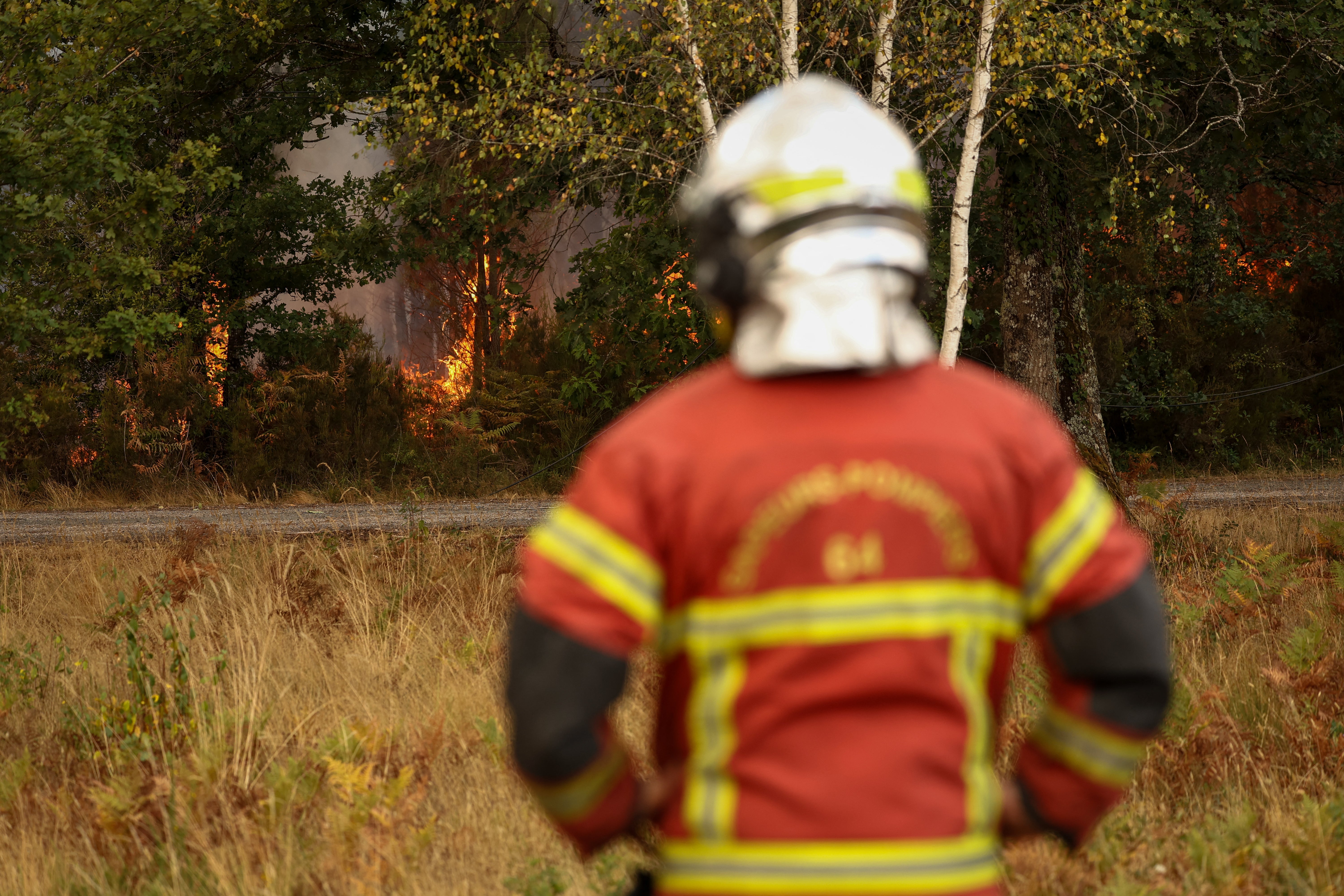 A firefighter stands on the edge of a burning area in Blagon, west of Bordeaux, on July 26, 2026 as a wildfire has been ravaging the forest north of the Arcachon Basin (Gironde) since July 22.