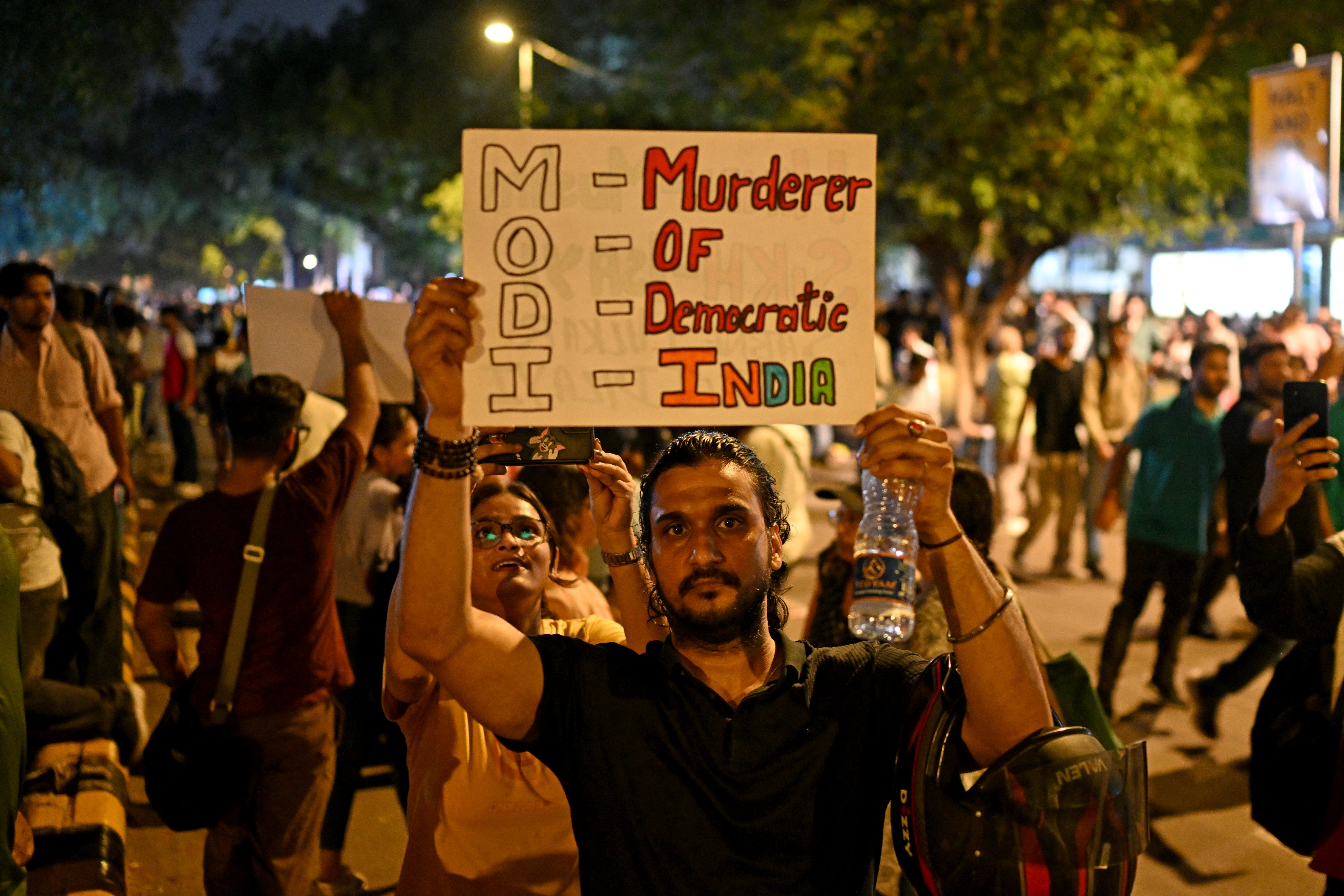A supporter of the Cockroach Janta Party (CJP) holds a placard as protesters celebrate the resignation of India's education minister Dharmendra Pradhan