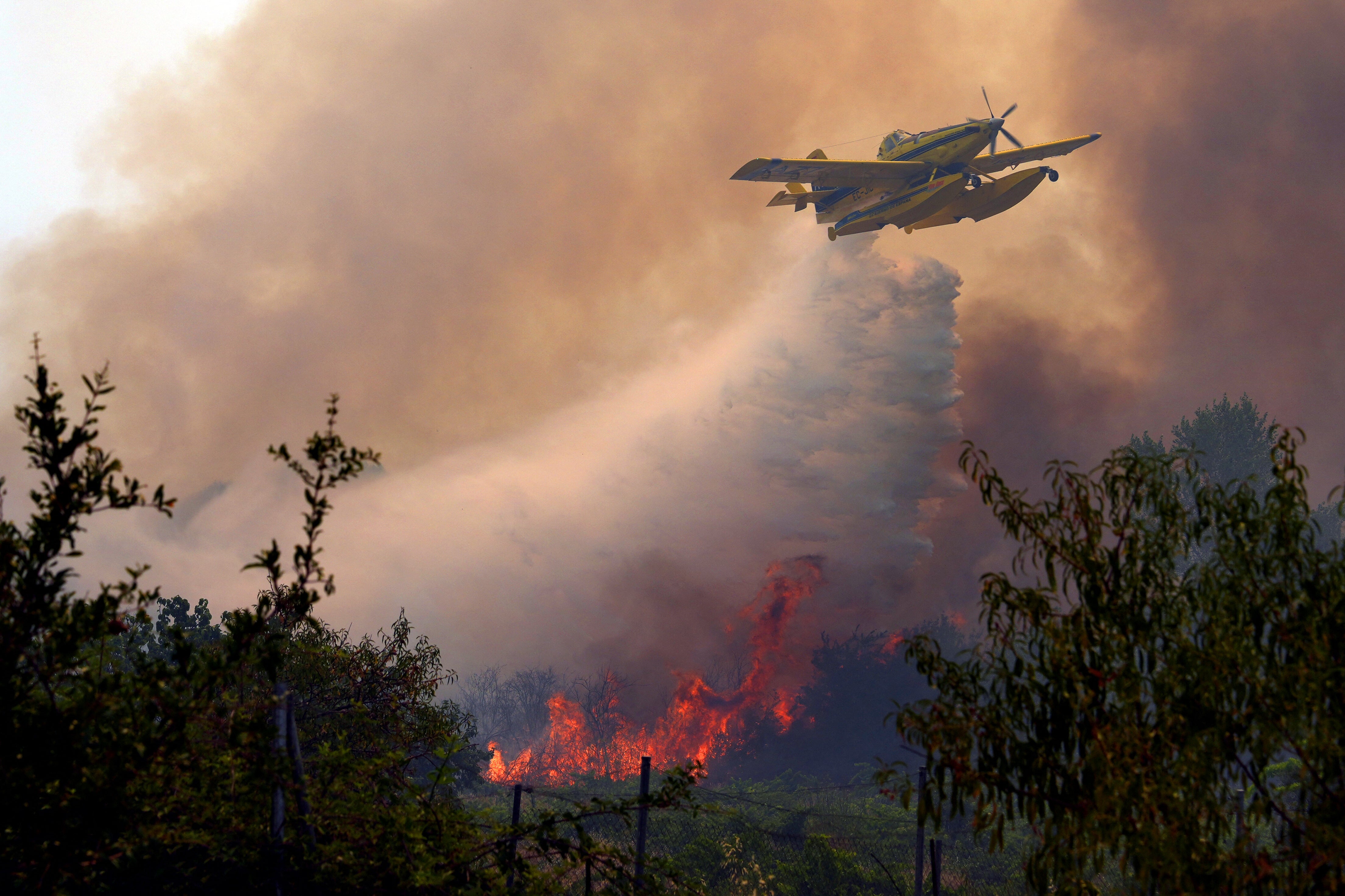 An aircraft dumps water over a wildfire burning near San Martin de Valdeiglesias, about 40 miles west of Madrid