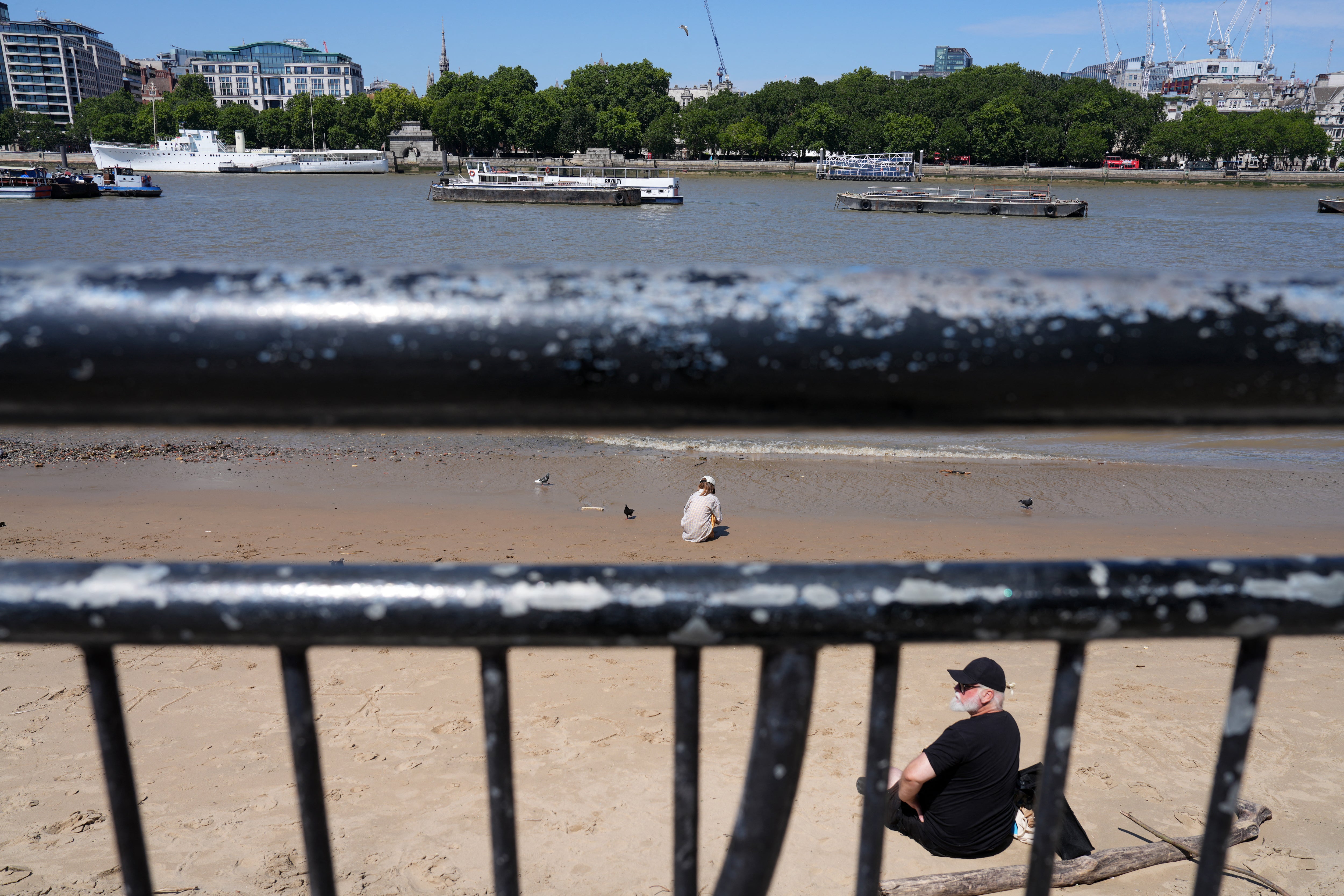People sit on the banks of the River Thames due to rising temperatures in early July