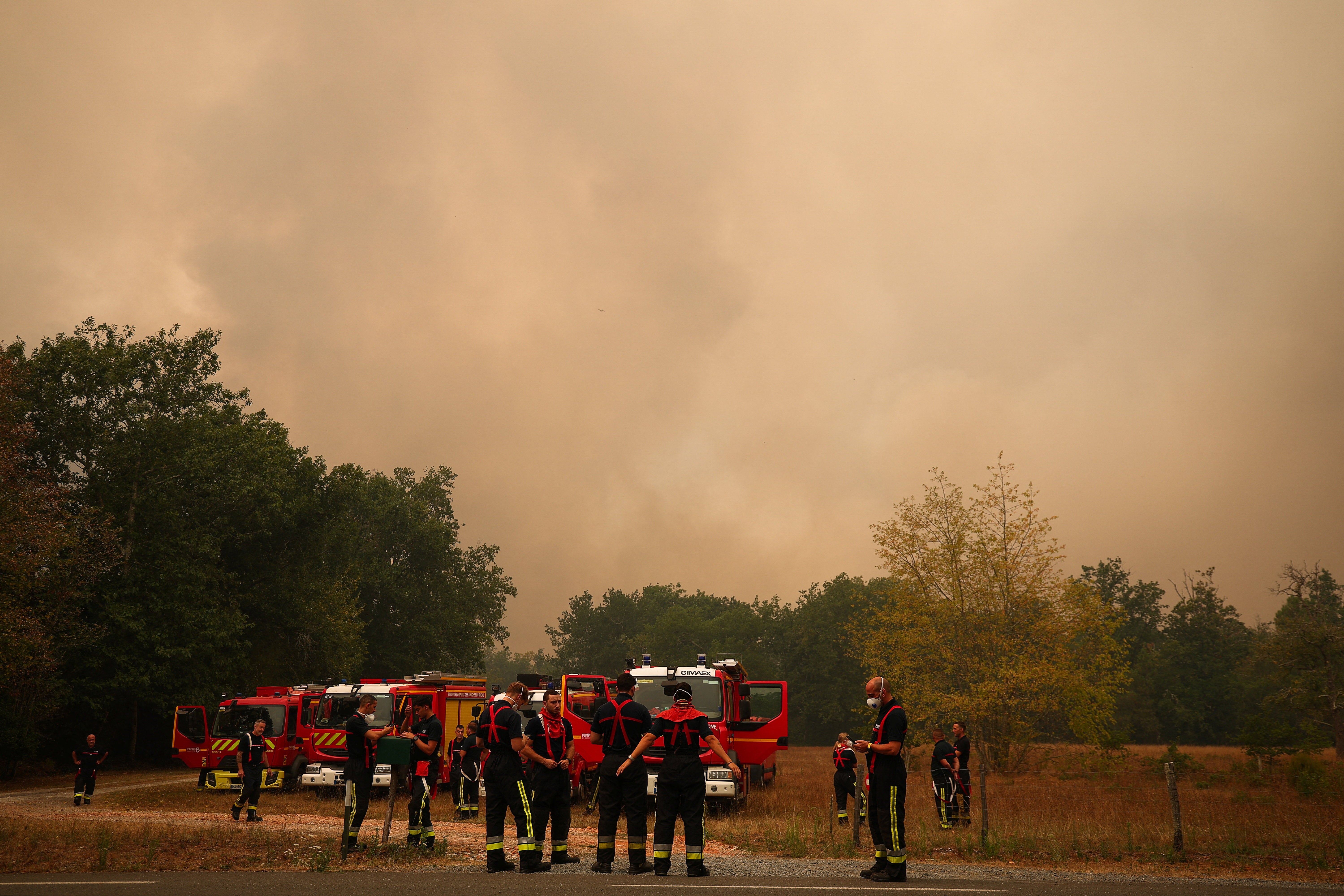 Firefighters stand close to fire engines, as a wildfire burns nearby, amid worsening drought conditions following a heatwave and water shortages across much of France, in Pierroton, Gironde, France, July 26, 2026. (Reuters)