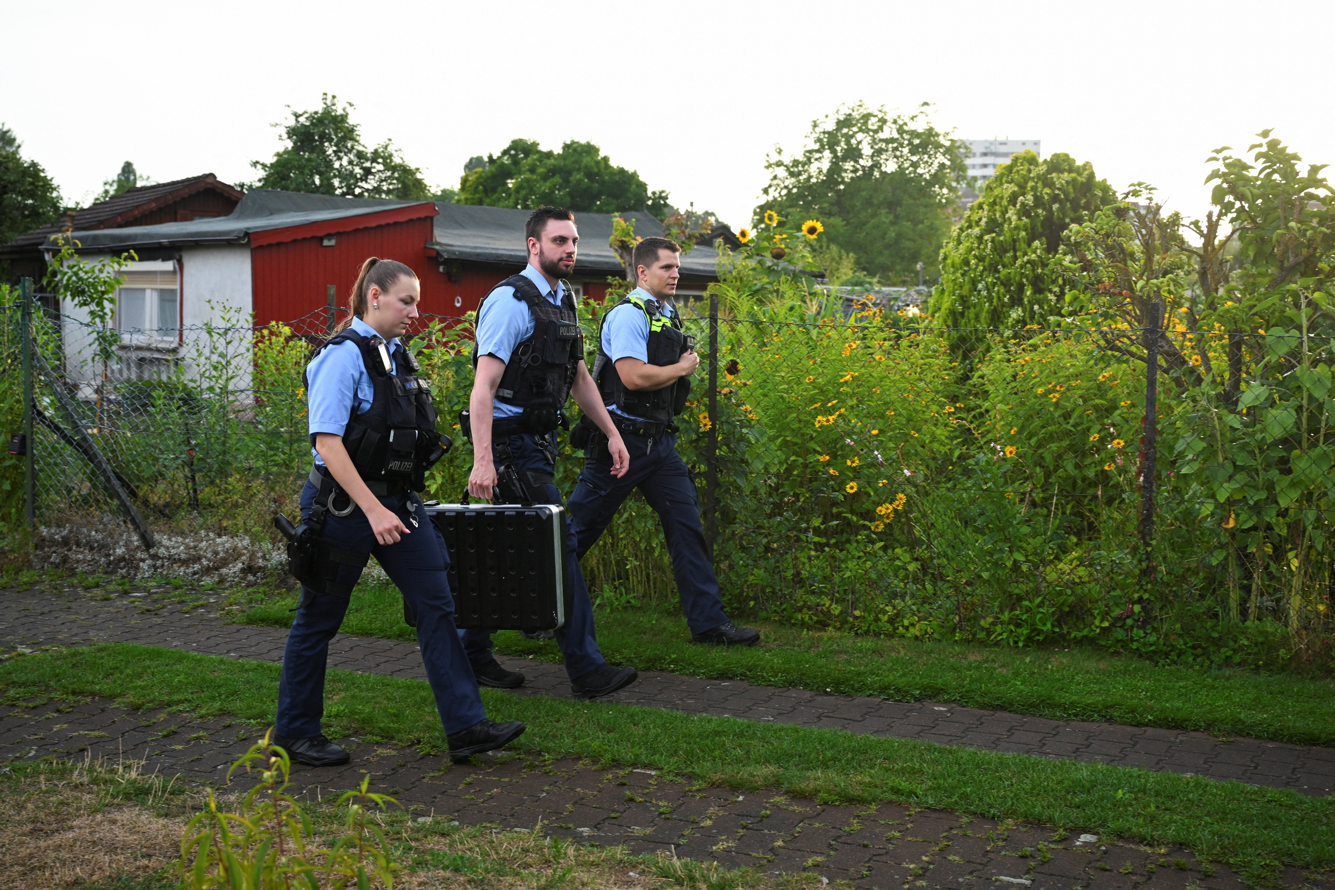 Police officers walk at an allotment garden complex in the Berlin suburb of Spandau, after a known Islamist, suspected of ramming a minivan into a crowd near Berlin's annual Christopher Street Day Pride parade on Saturday evening, was shot and killed in a police operation, in Berlin, Germany (Reuters)